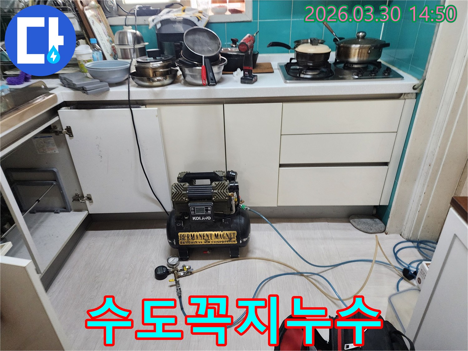 주방 하부장 안쪽에서-수도꼭지 연결 부위 누수를 확인하기 위해-공압 장비가 연결되어-정밀 검사가 진행 중입니다.