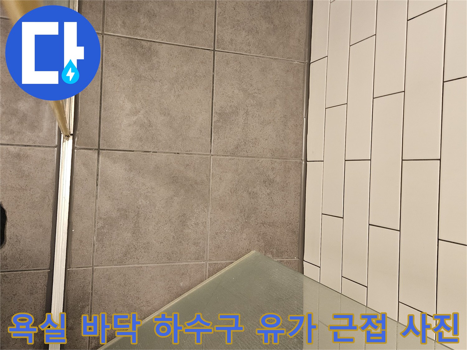 금속 재질의 하수구 트랩과 주변 회색 타일 면