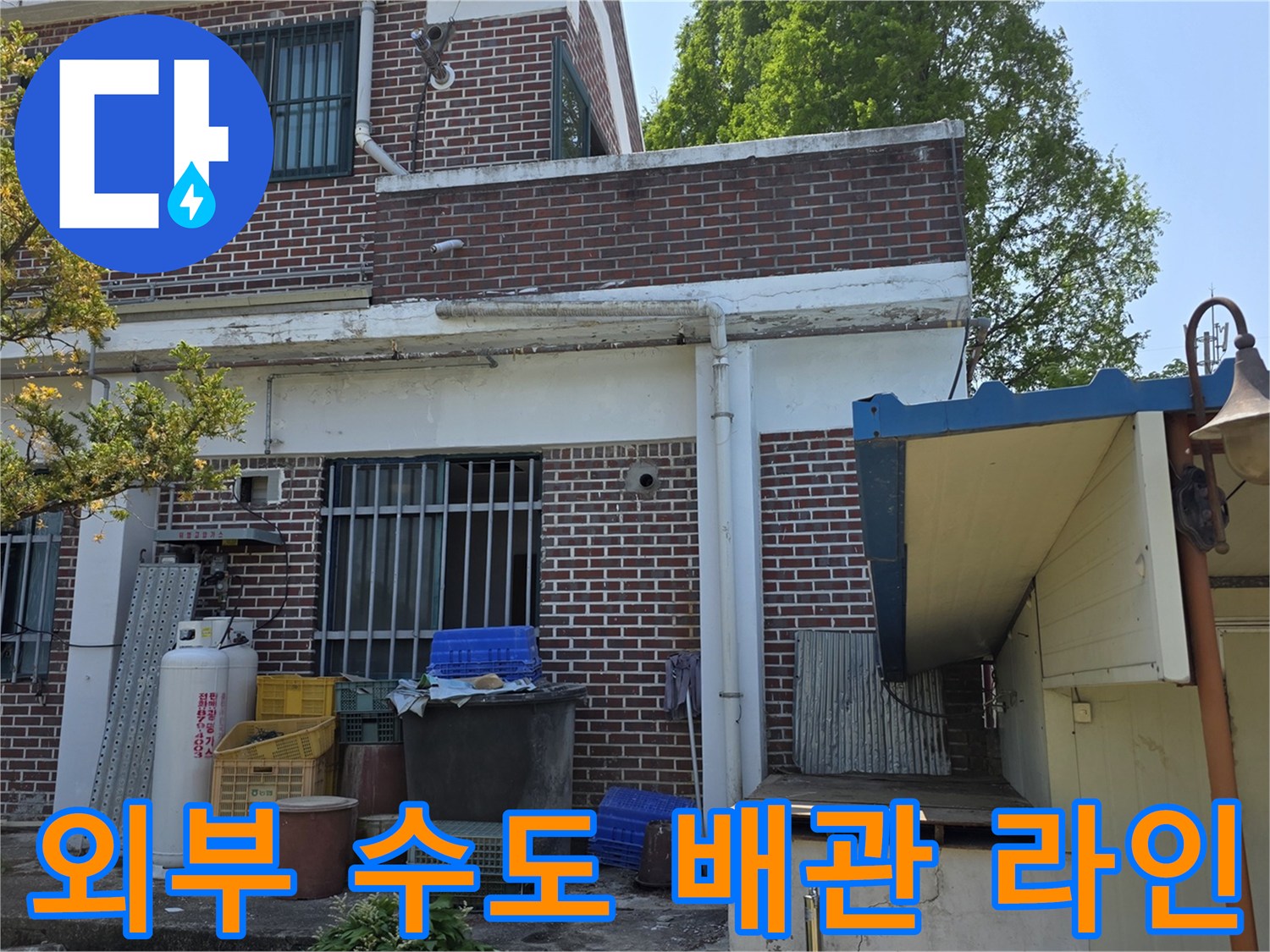 건물 외벽 하단의 외부 수도꼭지와 연결된 배관들의 모습입니다.