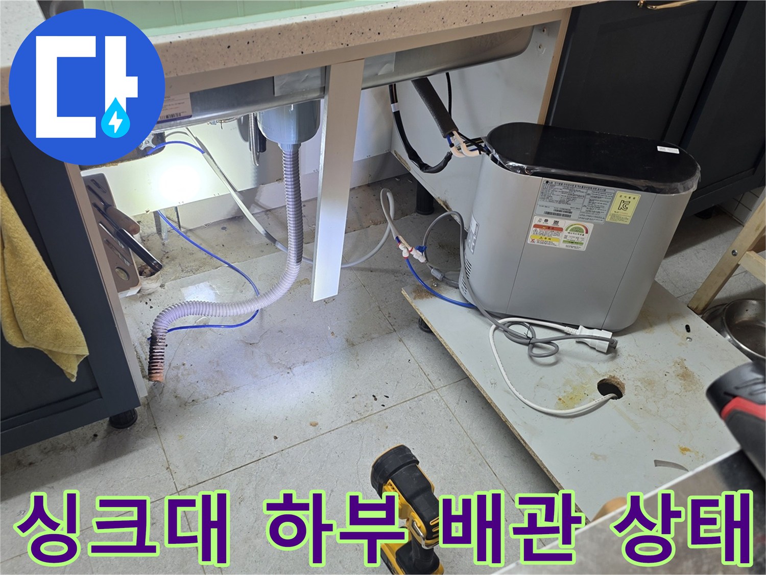 싱크대 아래쪽 배관과 주변 작업 도구가 놓인 현장 사진