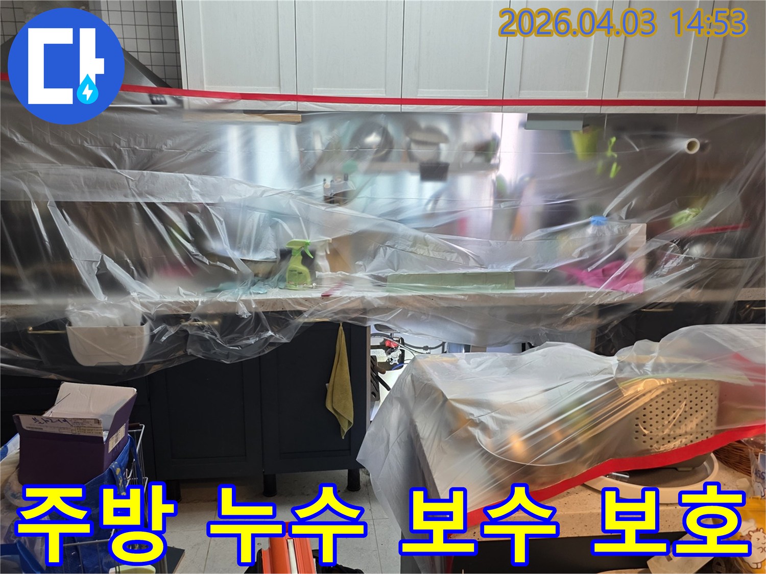 이 사진은 주방 싱크대 누수 보수 작업을 시작하기 전-주변 가구와 공간을 비닐로 안전하게 보호하는-보양 작업이 완료된 상태를 보여줍니다.