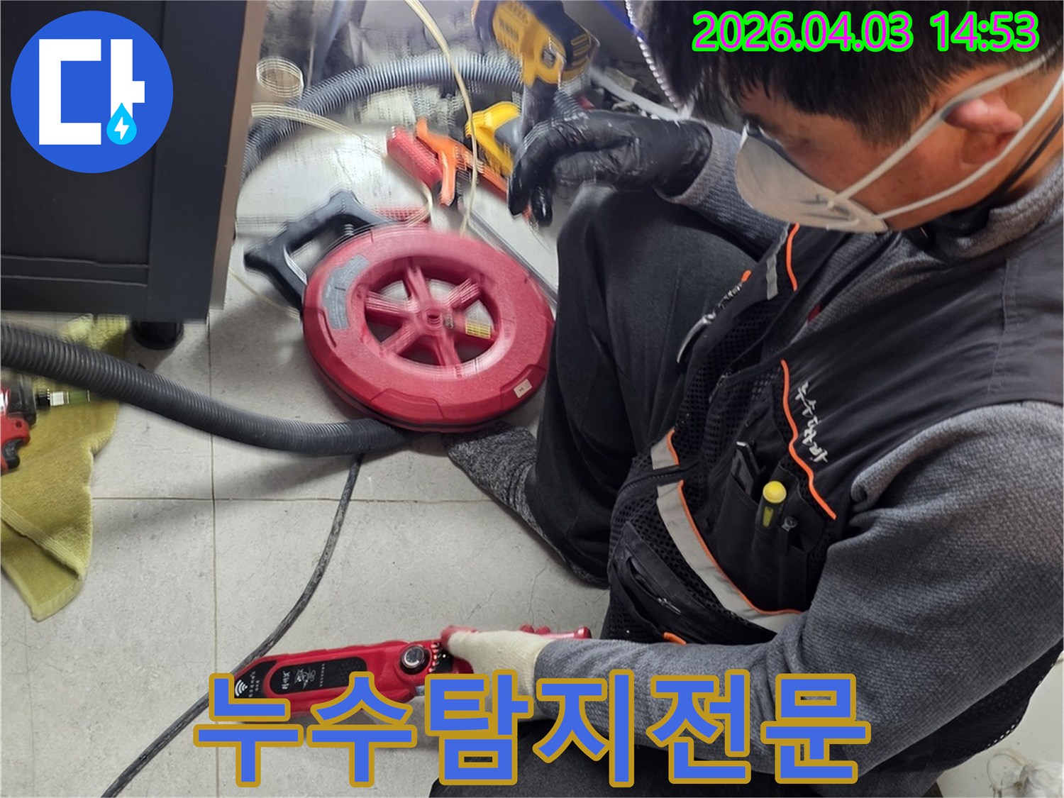 작업복을 입은 기술자가-누수 탐지 기기를 들고-타일 바닥의 미세 누수를-정밀하게 진단하고 있습니다.