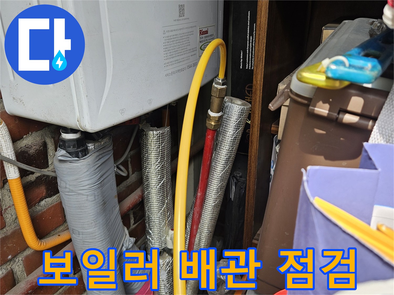 보일러실 내부의 은박 단열재로 감싸진 배관과 노란색 호스 모습