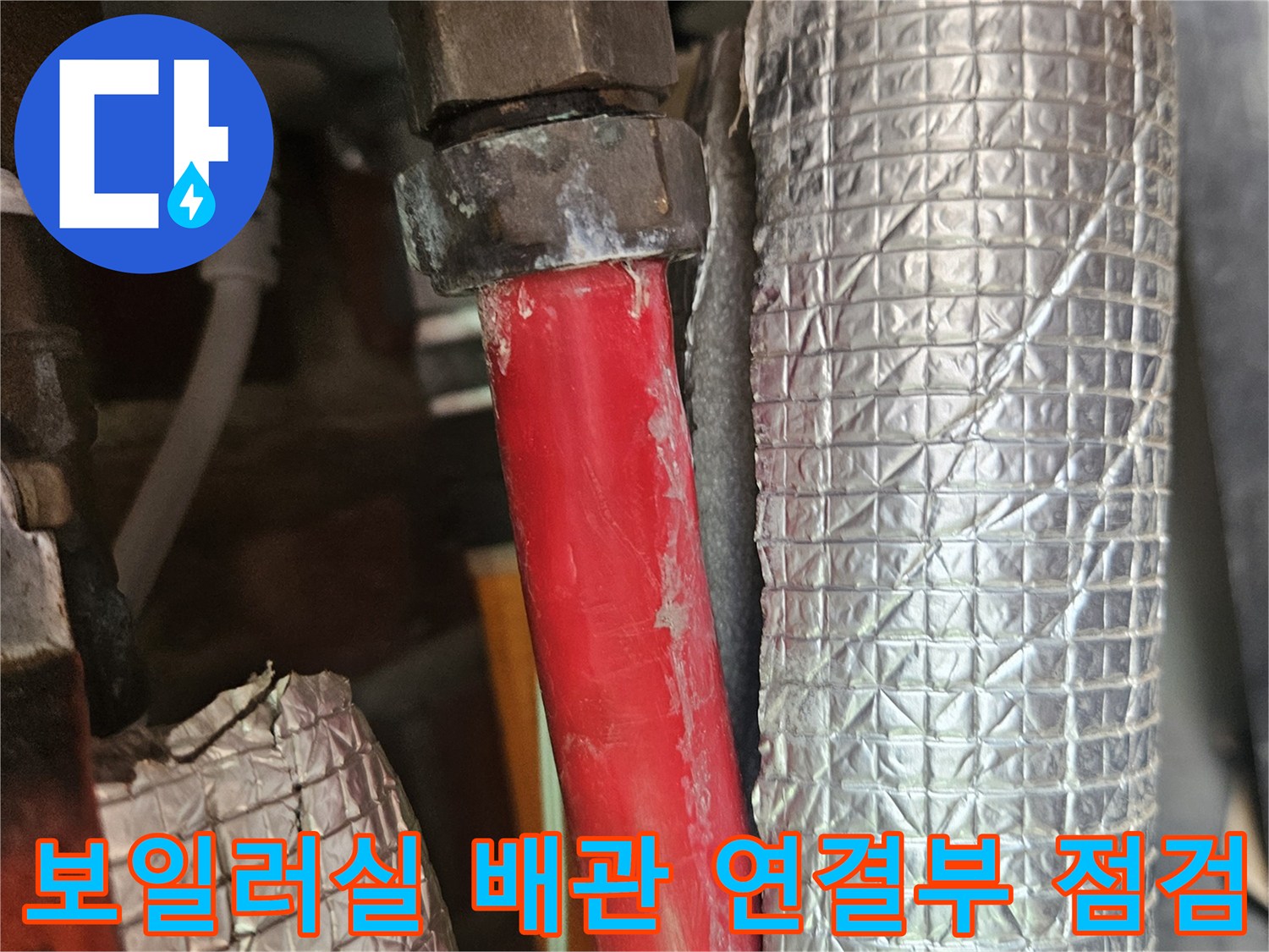 보일러실-은박 보온재로 감싸진 배관과 붉은색 온수 라인의 연결 부위를 정밀하게 확인하는 모습입니다.