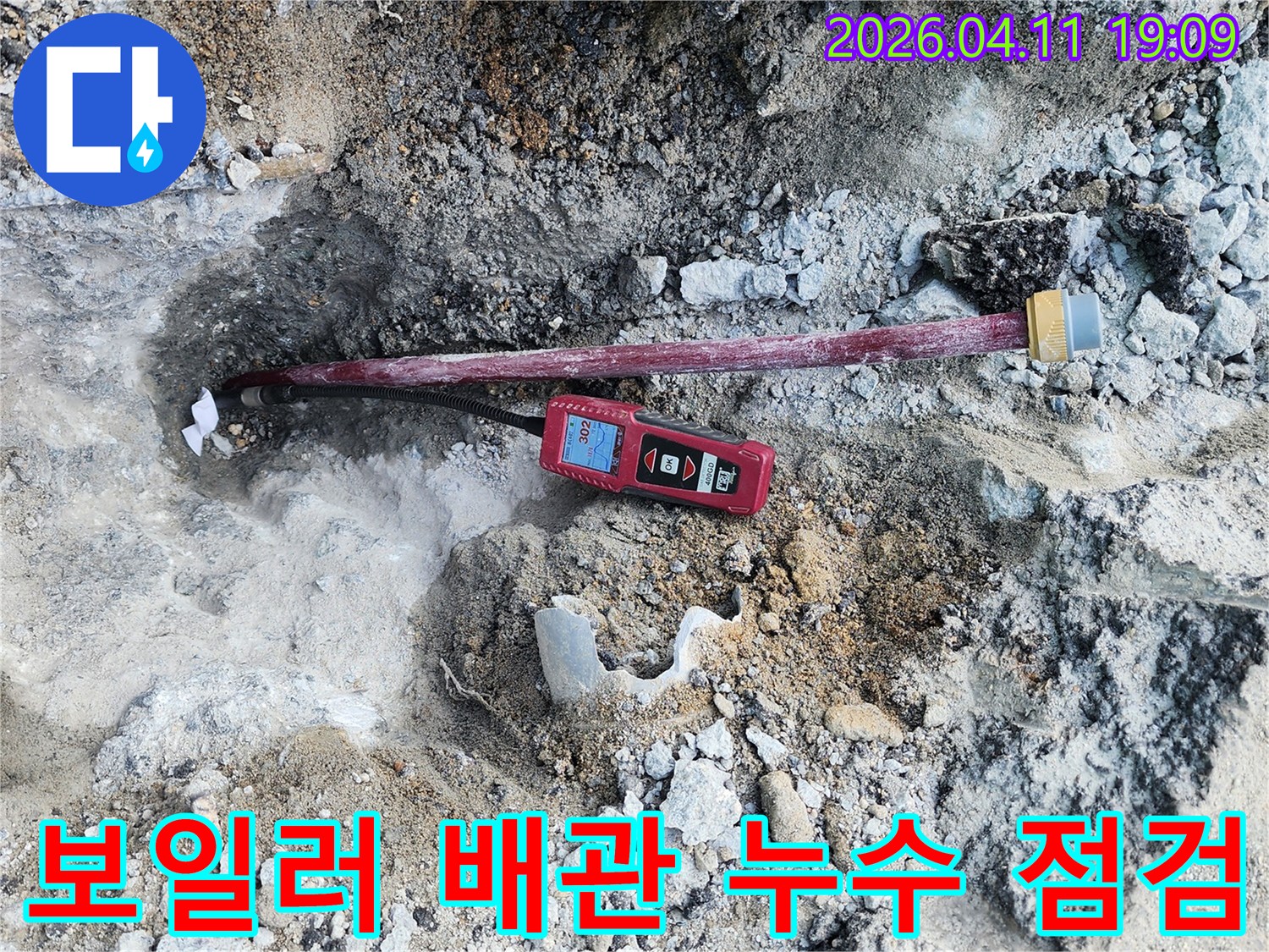 땅속에 노출된 배관과-배관에 연결된-누수 탐지 장비가 보이는-작업 현장입니다.