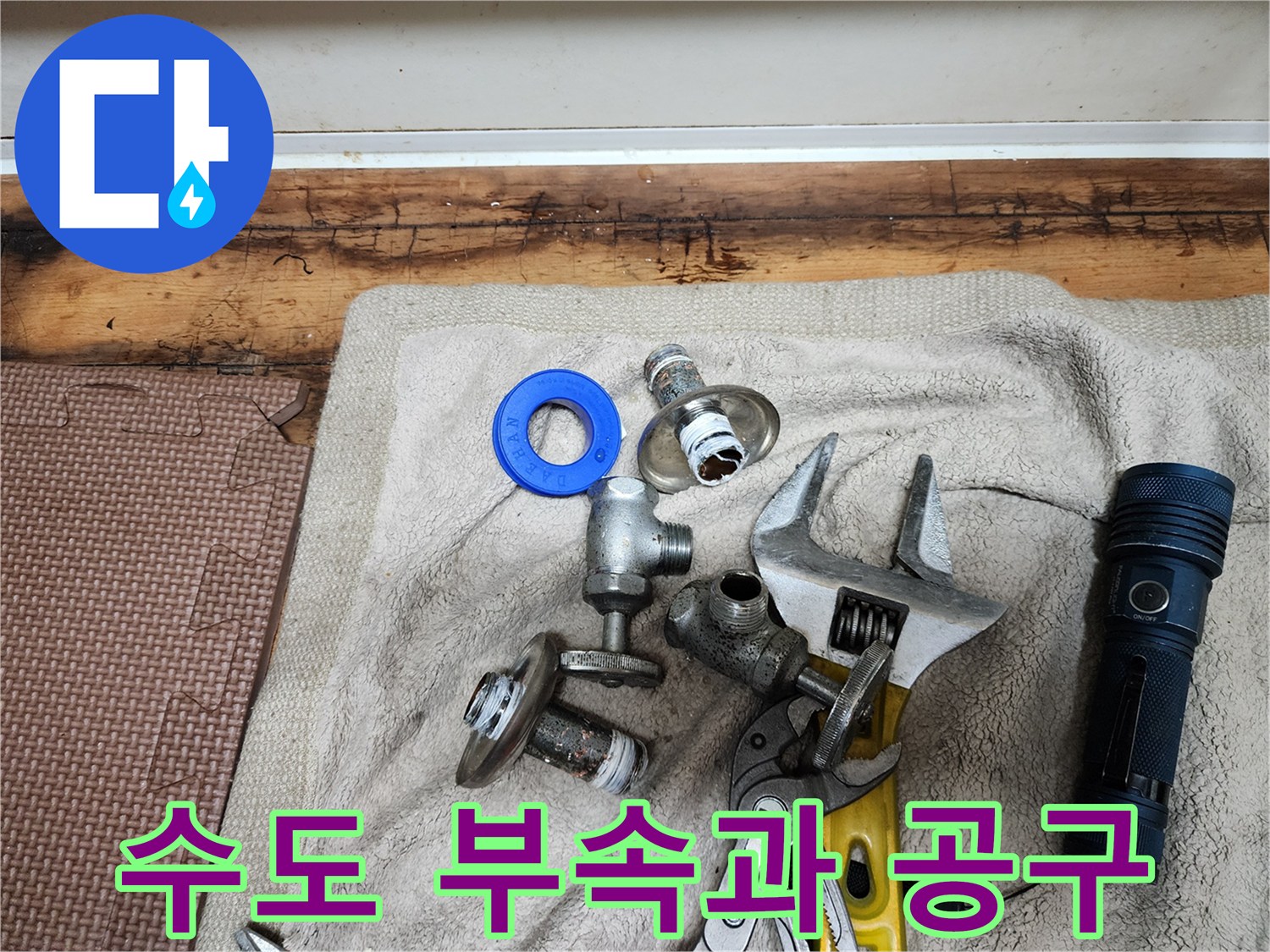 수도 밸브와 파란색 패킹-몽키 스패너와 손전등이 놓인 모습