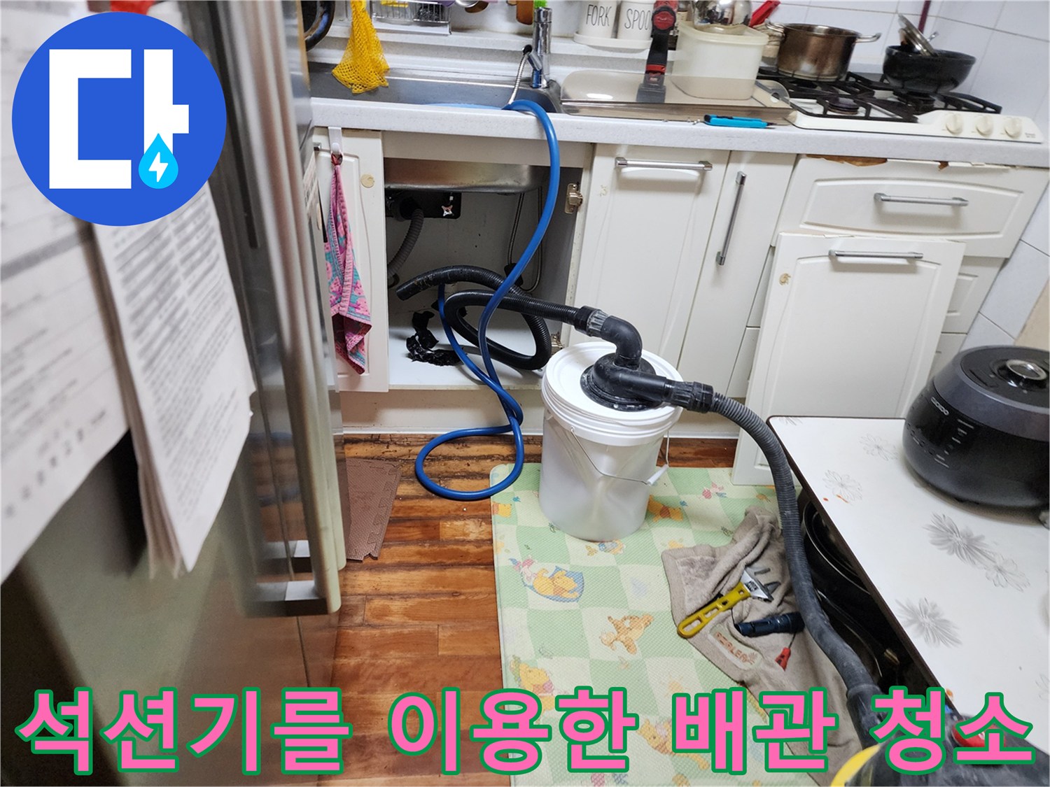 싱크대 밑 배수 호스에 석션 튜브를 연결하여 이물질을 뽑아내는 중입니다.