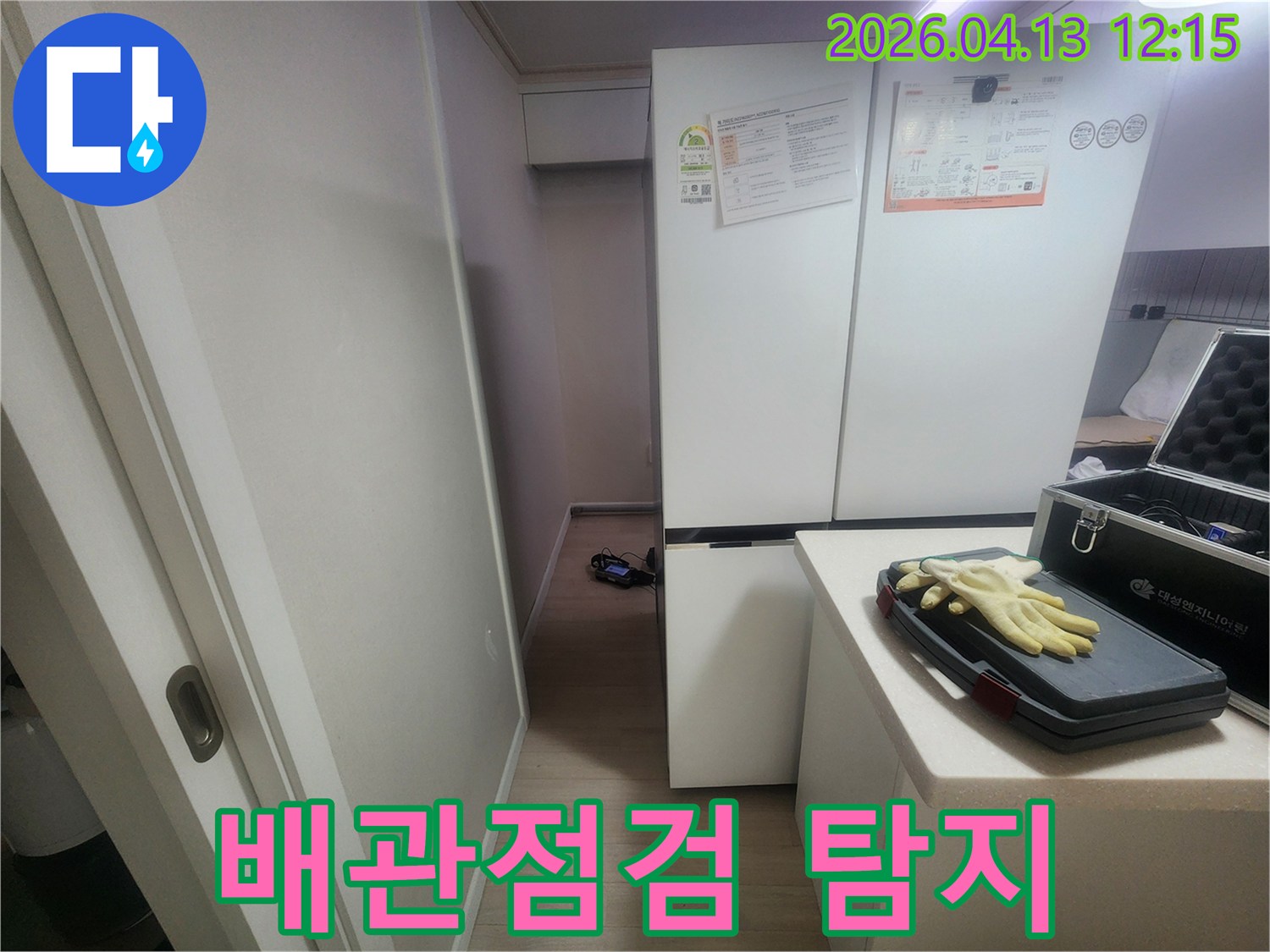 주방 냉장고 옆 공간에서-배관 누수 여부를 확인하기 위해-탐지 장비를 설치하고-작업을 준비하는 현장