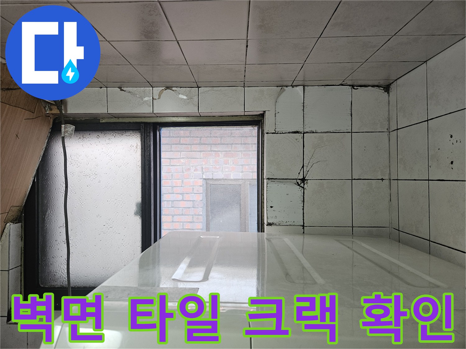다용도실 벽면의 타일 갈라짐과 창문 주변의 습윤 상태 이미지
