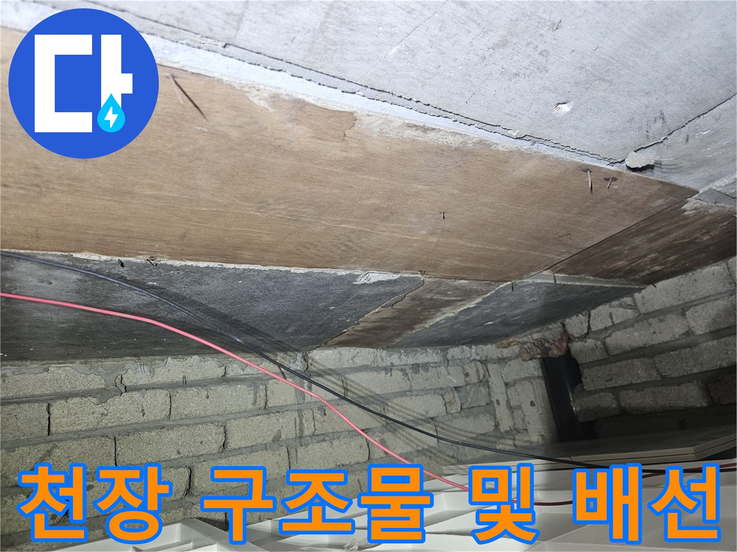 천장의 목재 판재와 벽돌 벽면 사이의 노출된 배선을 촬영했습니다.