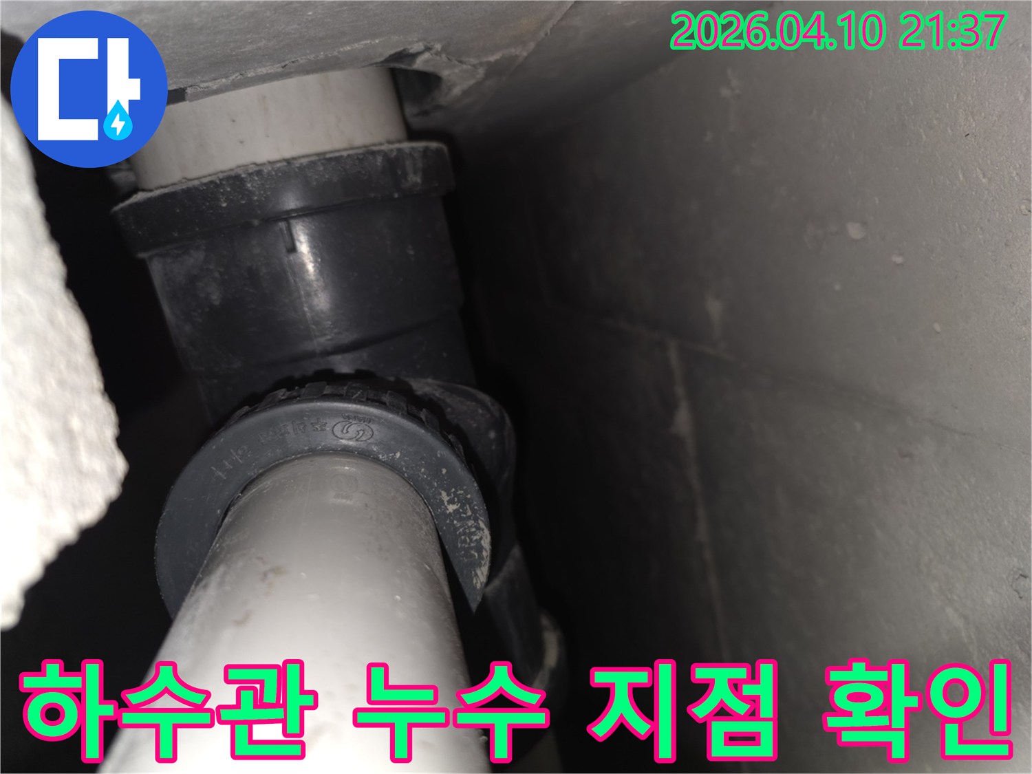 이 사진은-좁은 공간에 위치한-하수 배관의 연결 부위를-면밀히 검토하는 모습을-담고 있습니다