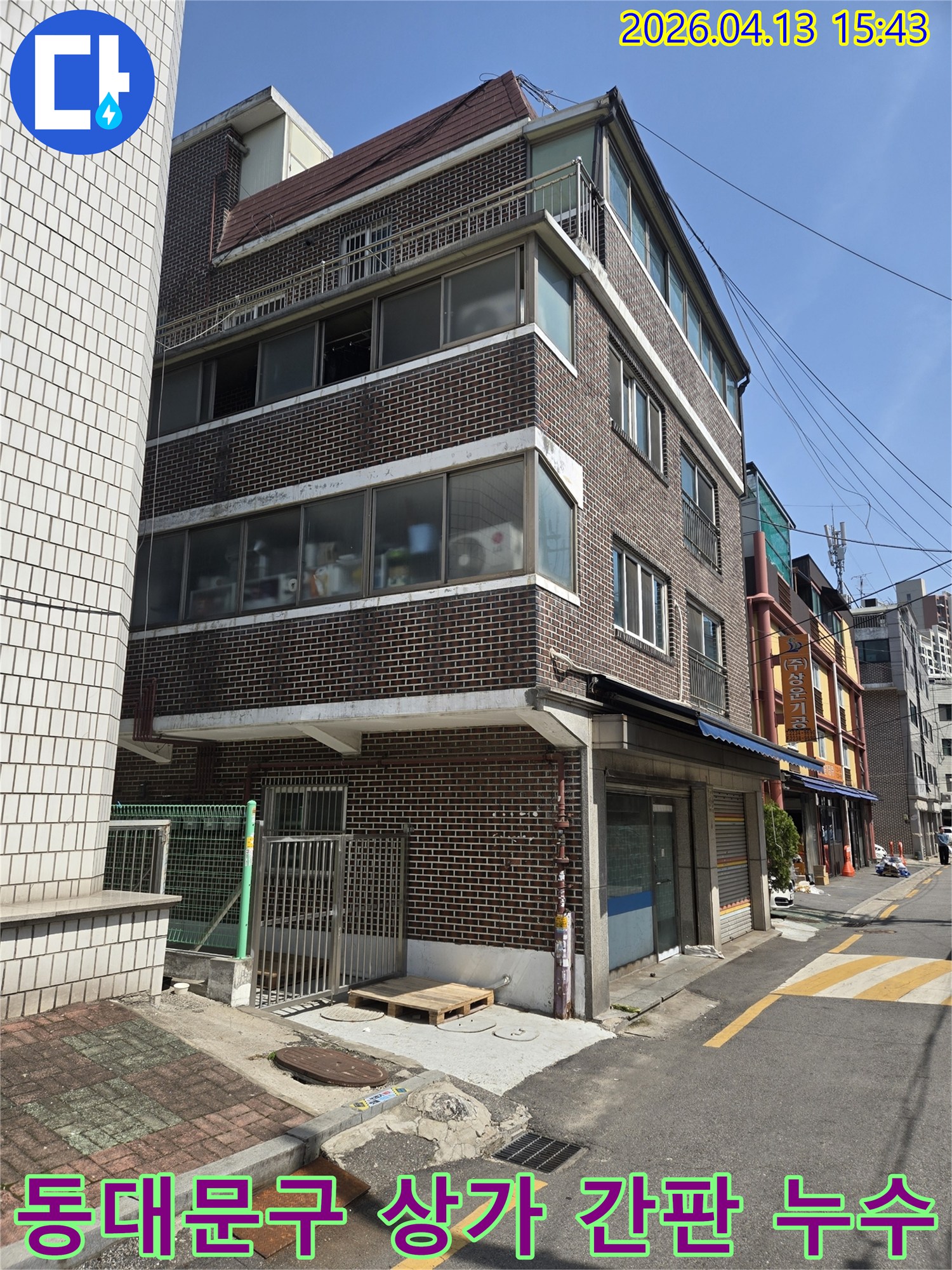 서울-동대문구의-상가-건물-외관을-보여주는-이-사진은-간판-설치-부위의-방수-문제로-인한-누수-원인을-찾기-위해-전문-엔지니어가-현장을-점검하는-모습입니다.
