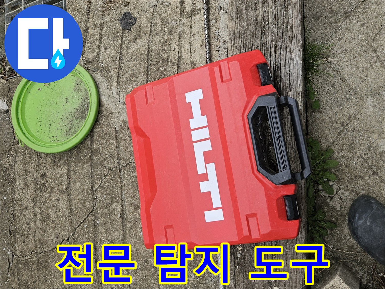 거친 지면 위에 놓인 붉은색 공구함과 작업용 부품들입니다.