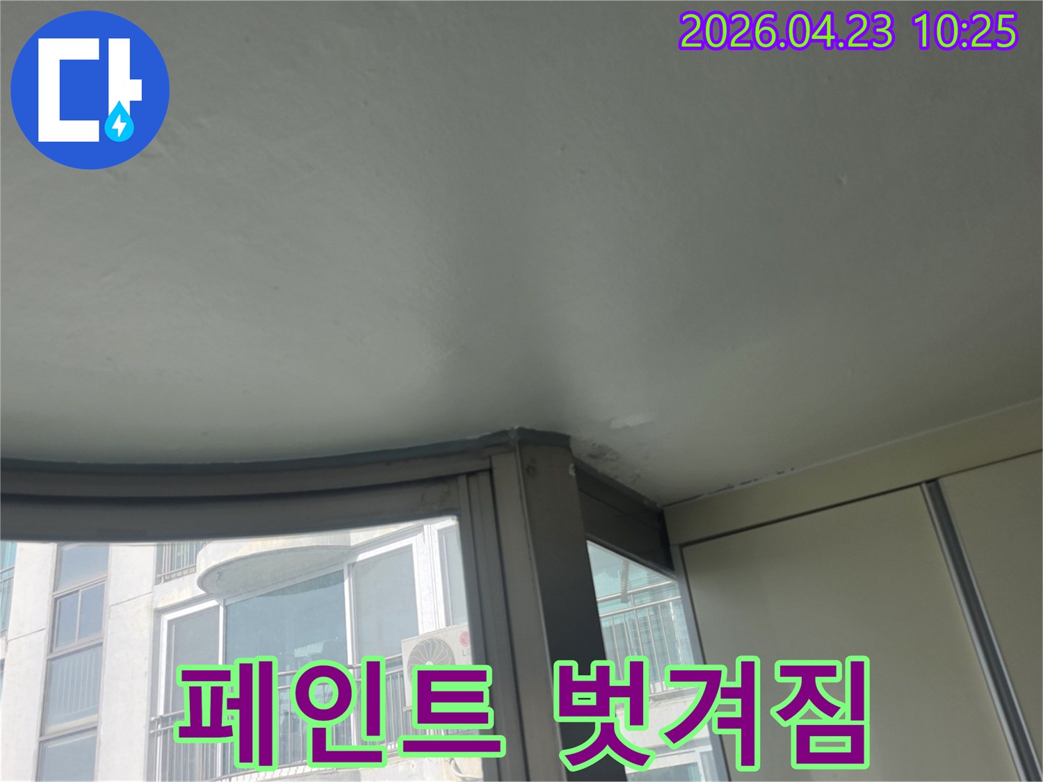 이 이미지는 아파트 베란다 창가 천장 페인트가 누수로 인해 벗겨진 모습을 담고 있습니다-물이 스며들어 마감재가 손상된 심각한 피해입니다