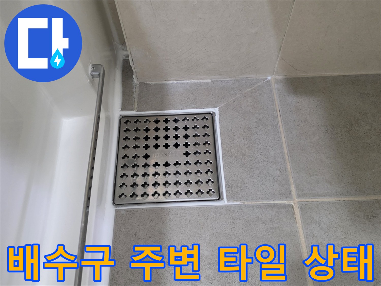 화장실 배수구 유가 주변의 타일 마감 상태를 촬영한 사진입니다.