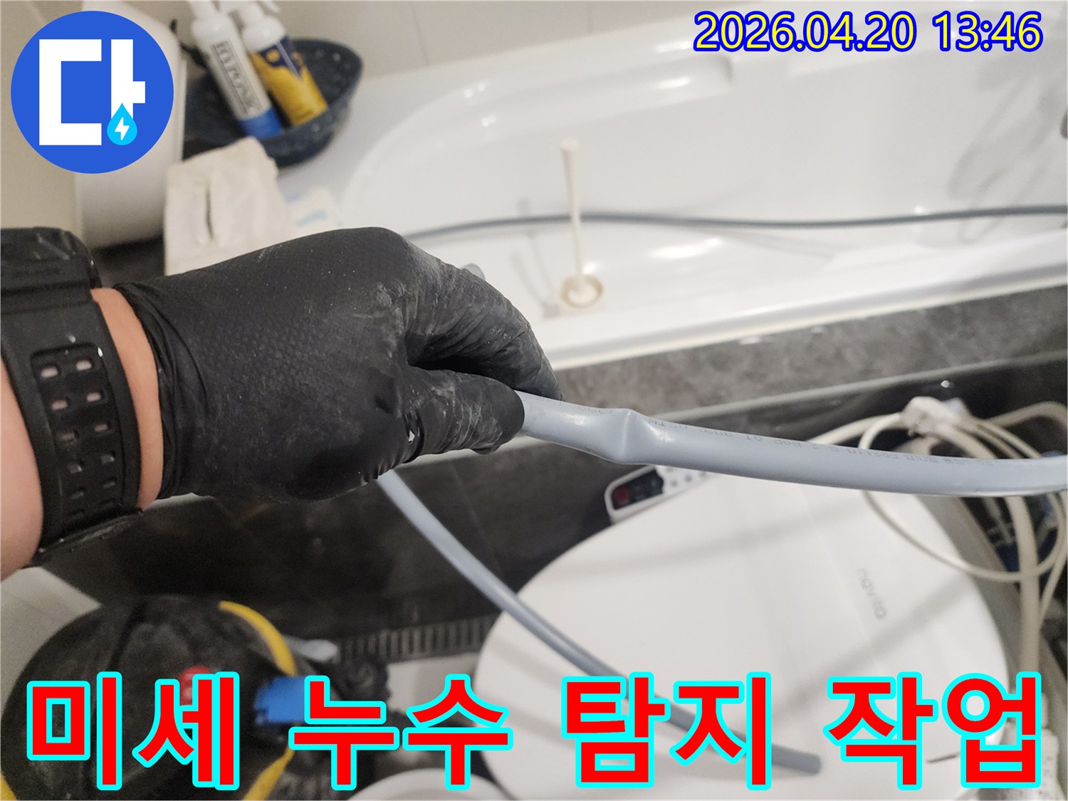 검은 장갑을 낀 엔지니어가 욕실 배관의-미세한 누수 지점을 찾아내기 위해-육안으로 집중적으로 탐지하고 있습니다.