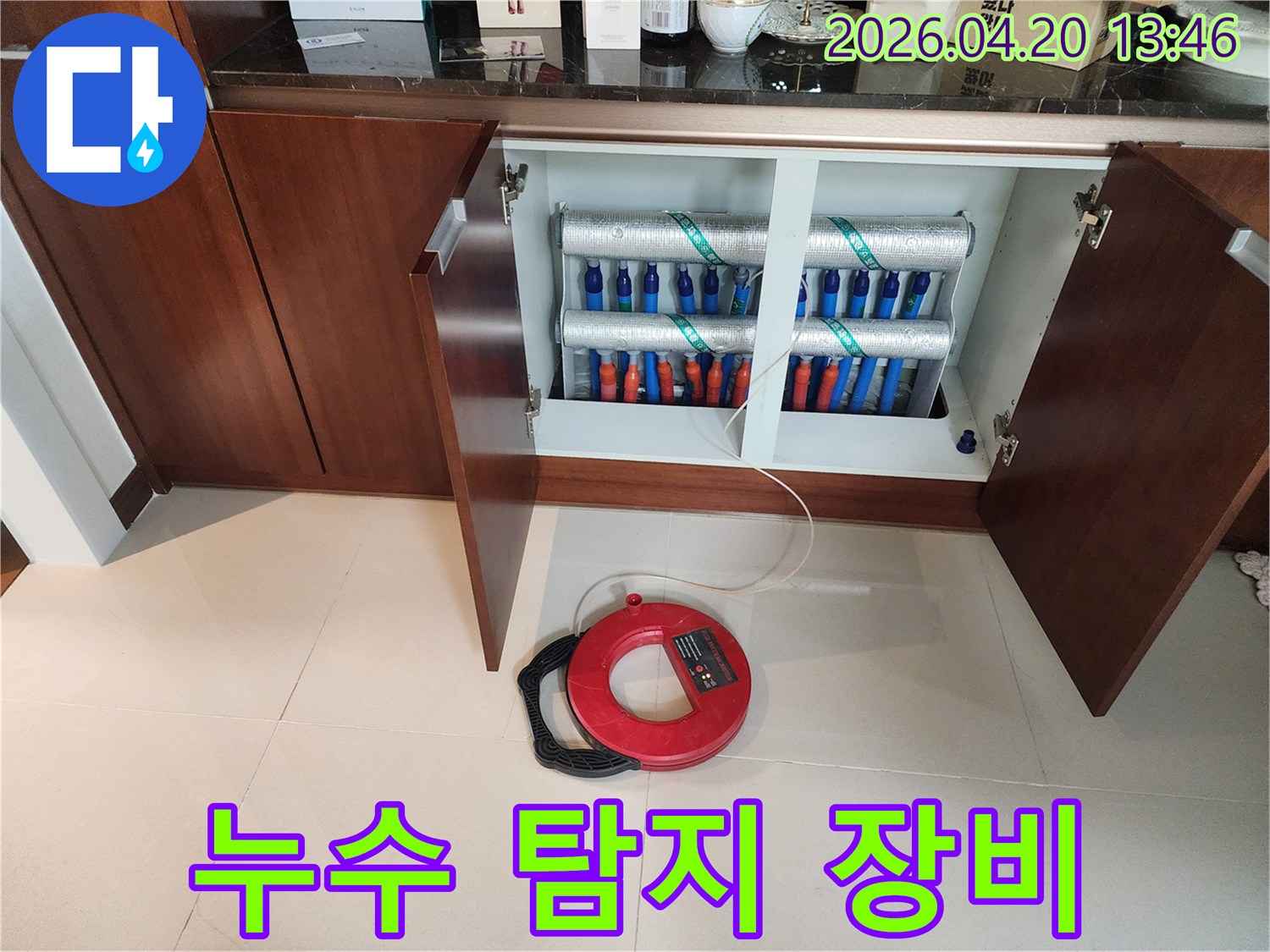 난방 분배기에서-누수 징후가 발견되어-전문가가 탐지 장비를 이용해-정밀하게 검사하는 현장입니다