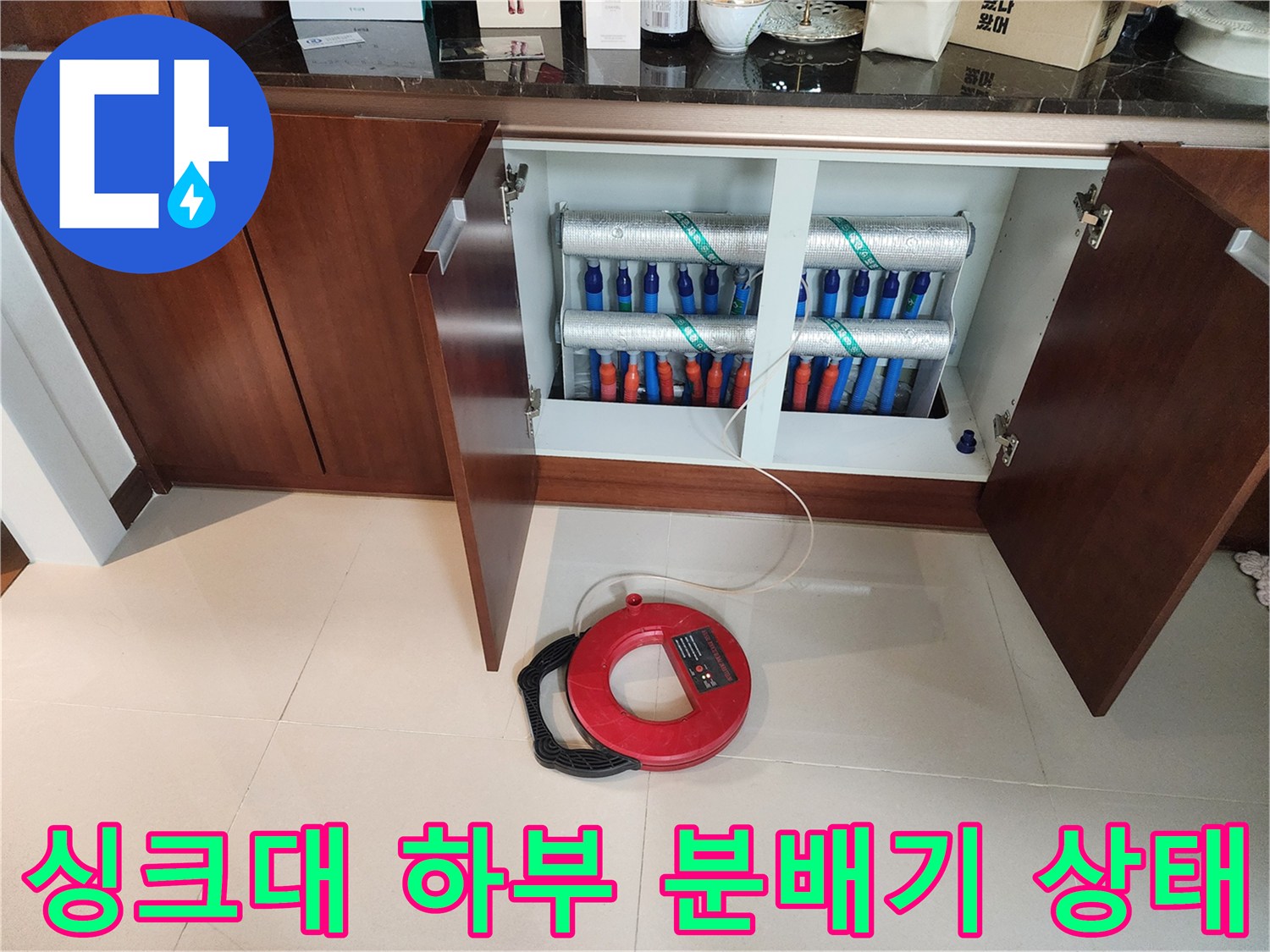 분당 아파트 싱크대 하단에 노출된 배관 분배기와 탐지 장비 모습