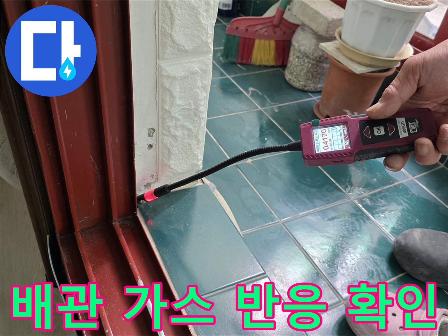 탐지 장비의-센서 부분을 타일 틈새에 가져다 대어 누수를 감지하는 장면