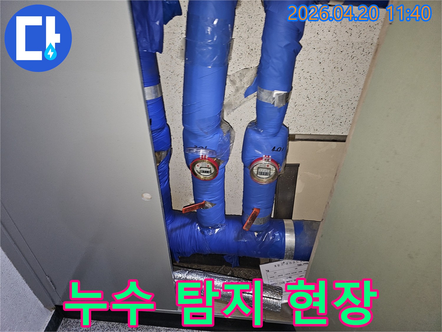 파란색으로-단열된-파이프와-두 개의-수도계량기가-설치된-공간의-누수-확인-사진입니다.
