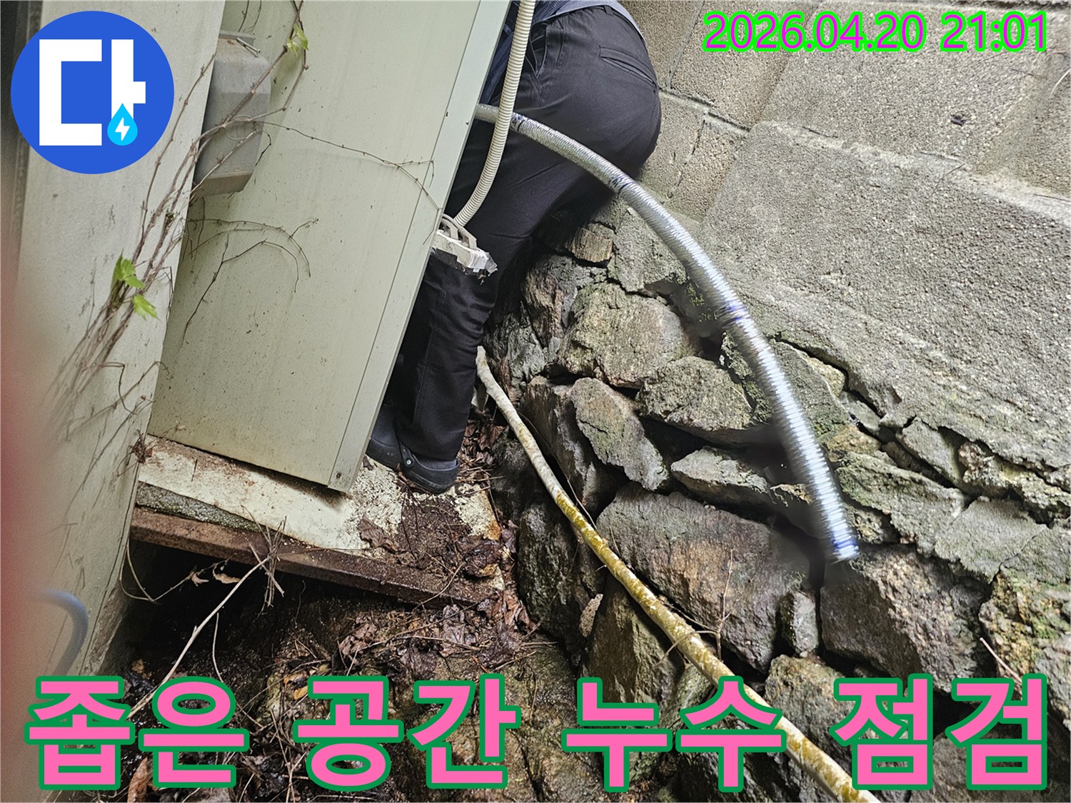 건물 외벽 아래-협소한 공간에서-누수 지점을 찾아내기 위해-탐지 작업을 진행하고 있습니다.