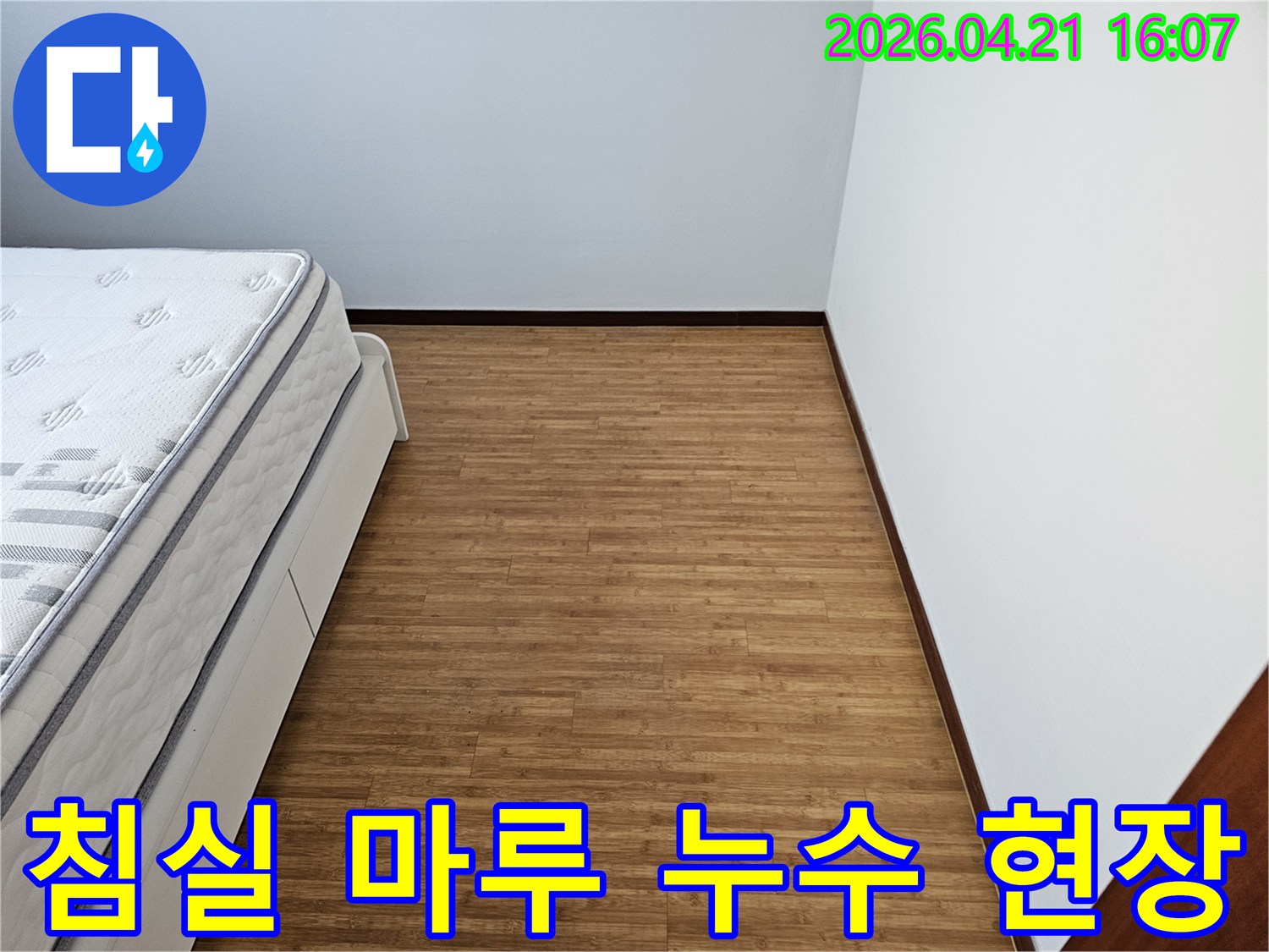 침대와 하얀 벽면- 그리고 나무 질감의 마루 바닥- 누수 탐지 작업을 위한- 준비된 침실 공간