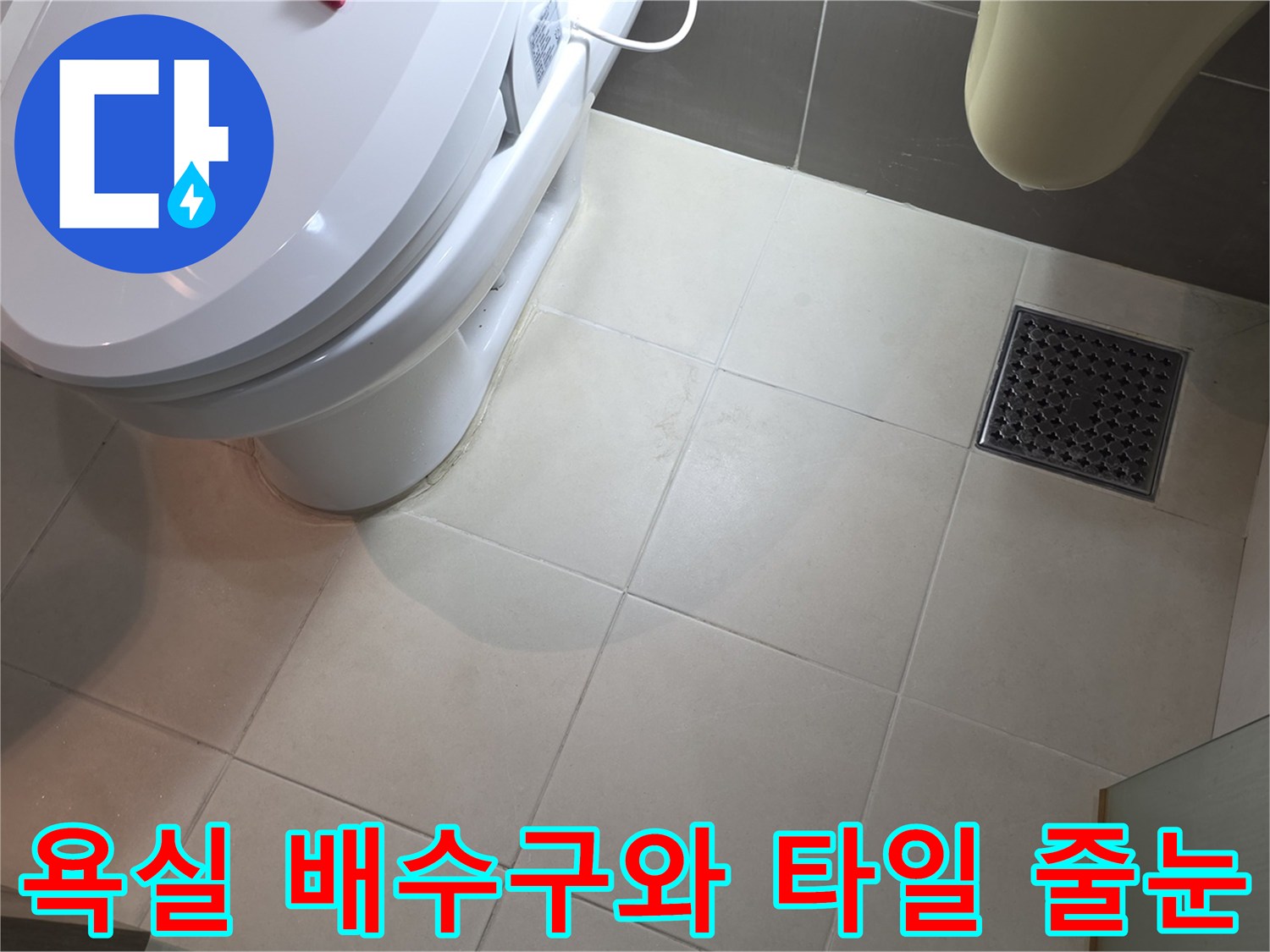 변기 옆 배수구 주변의 타일 배열과 유가 상태를 촬영한 사진입니다.