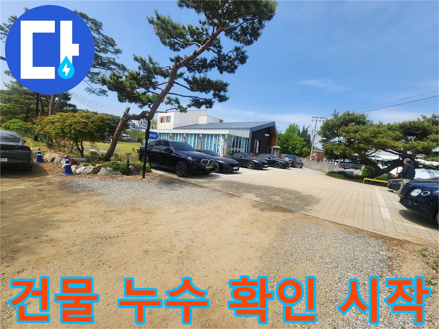 누수 문제 해결을 위해 방문한 건물의 외부 전경입니다-주차된 차량들과 푸른 나무들이 보입니다