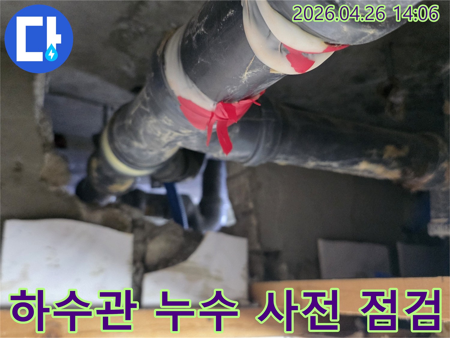 이 이미지는 아파트 하수관에서-누수 보수를 위한 사전 점검으로-빨간 테이프로 표시된 지점을-전문가가 면밀히 확인하는-과정을 보여줍니다.