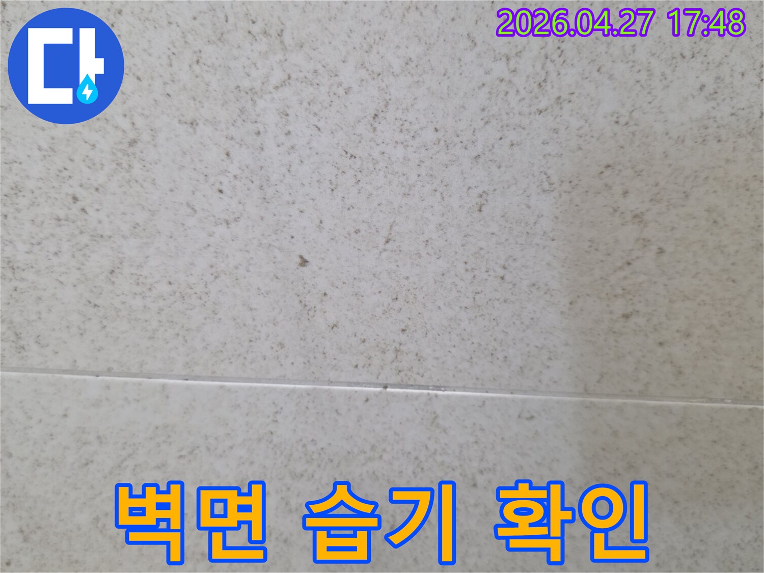 벽면에 나타난 습기 자국을 클로즈업한 이미지-누수로 인한 물기 침투의 명확한 증거를 보여줍니다