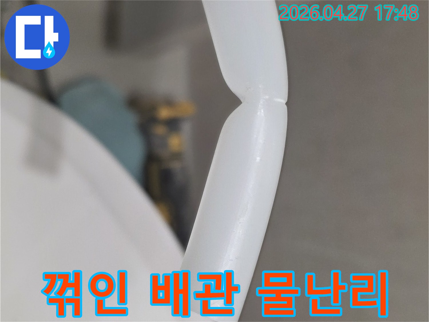 흰색 플라스틱 배관이 심하게 꺾여-물난리 발생 위험이 있는 상태를 보여주는 이미지입니다-즉각적인 조치가 필요한 손상 부위입니다.
