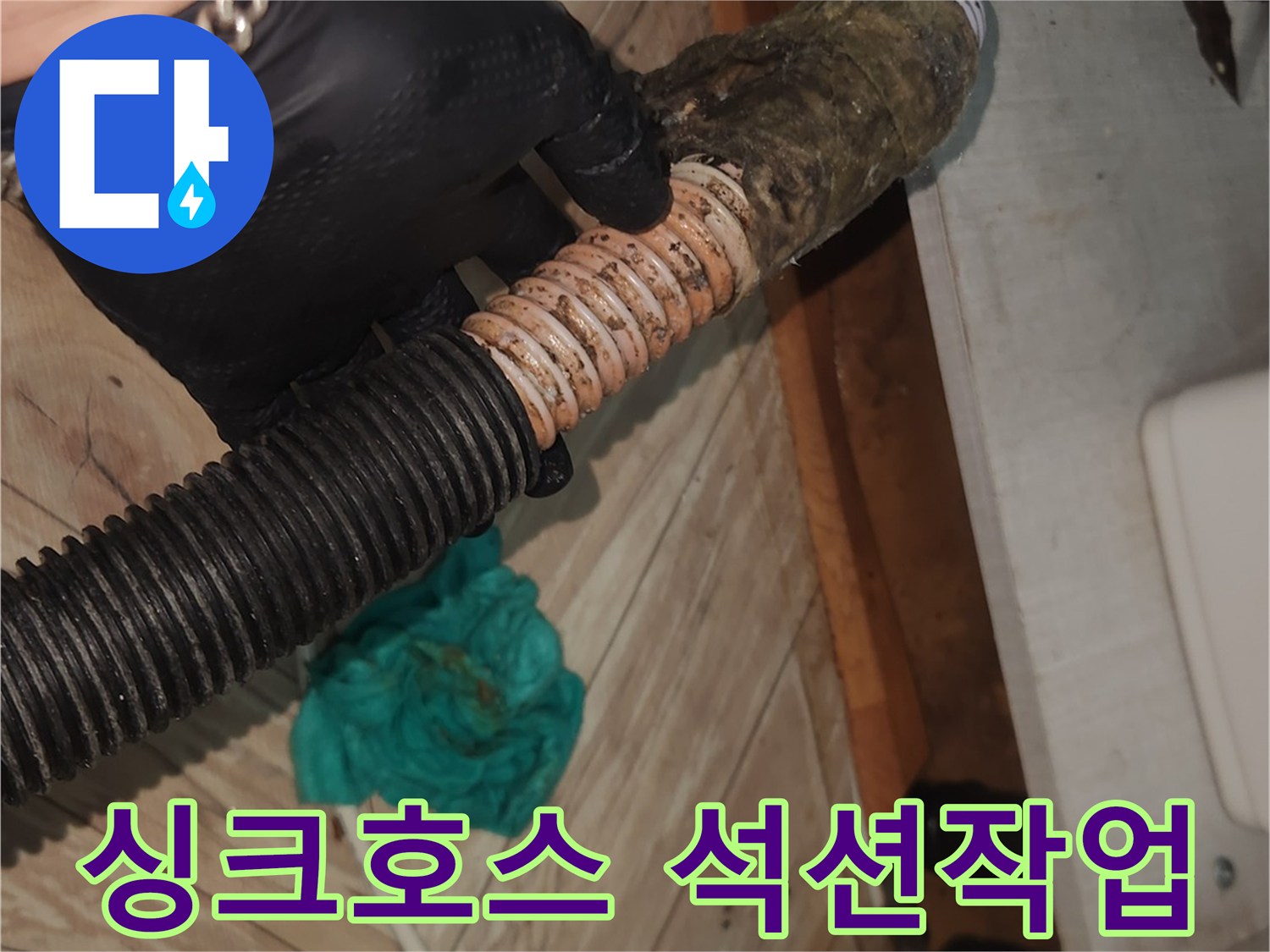 검은 장갑을 낀 손이-오랜 사용으로 찌꺼기가 쌓인 싱크대 배수 호스를-꼼꼼하게 확인하며-석션 클리닝을 준비하는 모습