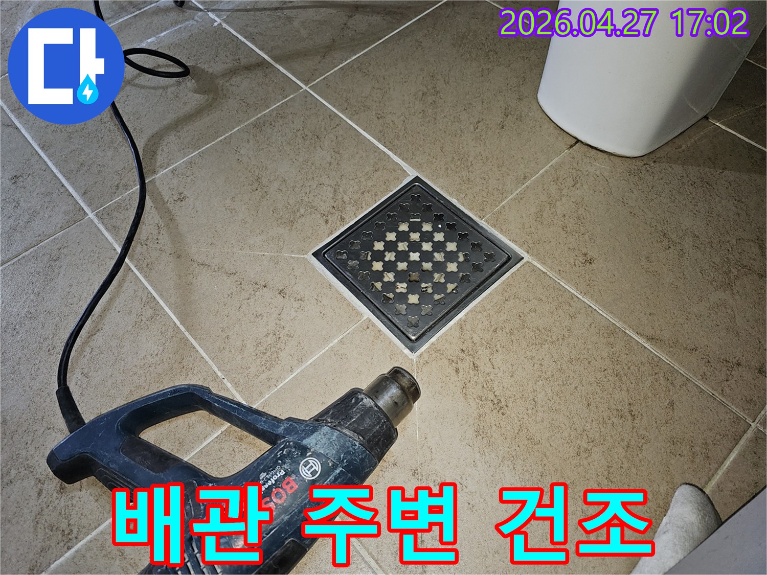 누수 보수 작업 후-전문가가-히팅건으로-배수구와 배관 주변을-건조하며-안정성을 확보하는 모습입니다.