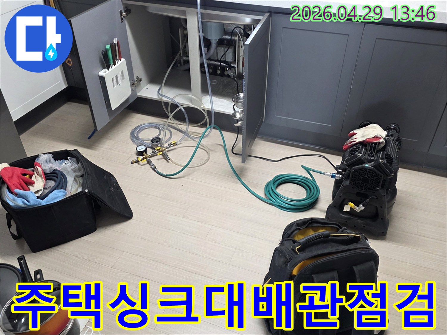 비산동 주택의 주방 싱크대 하부에서-누수 확인을 위한-배관 점검 장비와-호스를 연결하여-테스트를 준비하는 모습입니다