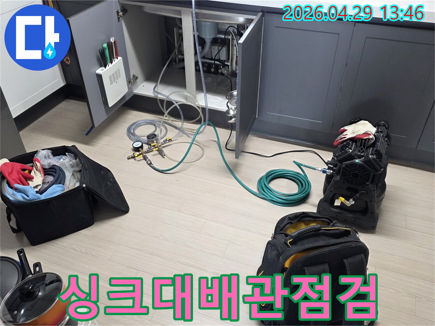싱크대 하부장 내부에서-누수 여부를 확인하기 위한-배관 점검 장비와-호스를 연결하고-압력 테스트를 준비하는 모습입니다