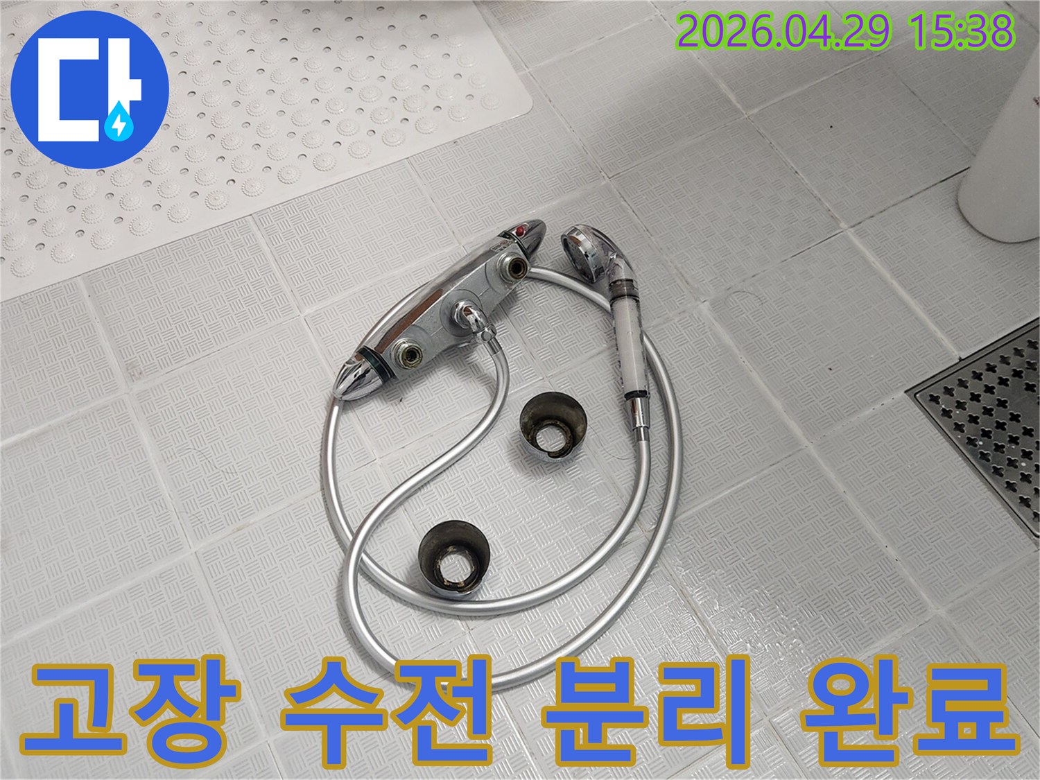 욕실 바닥에-수리 작업을-위해-고장난-샤워 수전이-분리되어-놓여있는-모습입니다