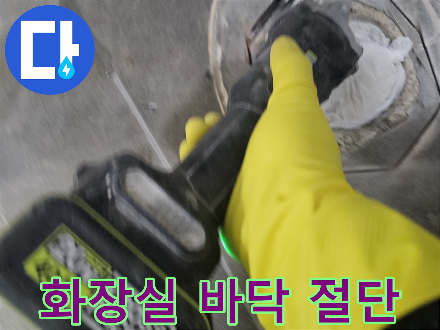 노란 장갑을 낀 작업자가-전동 커터로-오수 배관 주변의 바닥 타일을-정확하게 잘라내어-절단하는 모습입니다.
