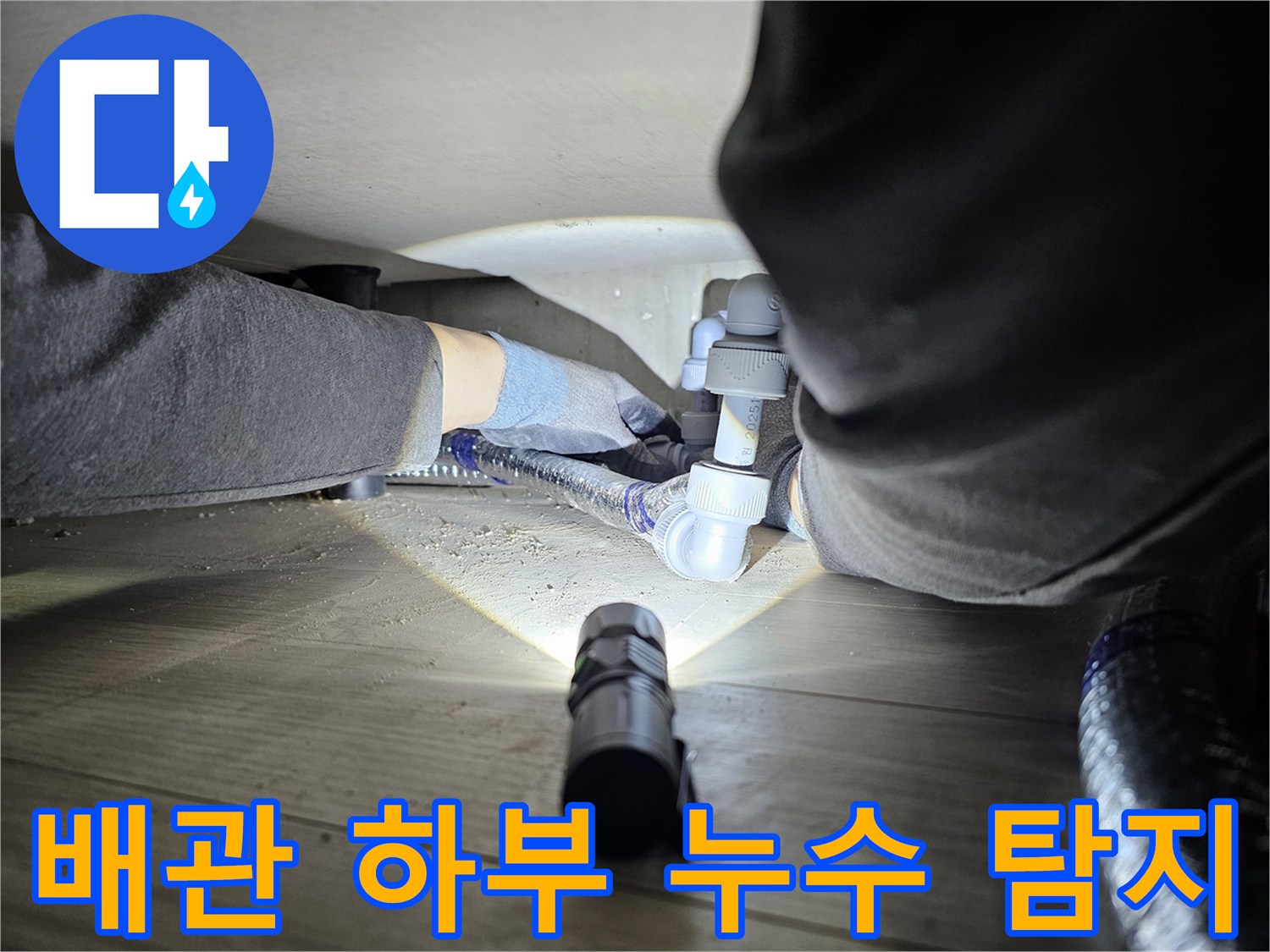 누수-전문가가-손전등을-사용하여-어두운-배관-하부를-정밀하게-살피는-장면