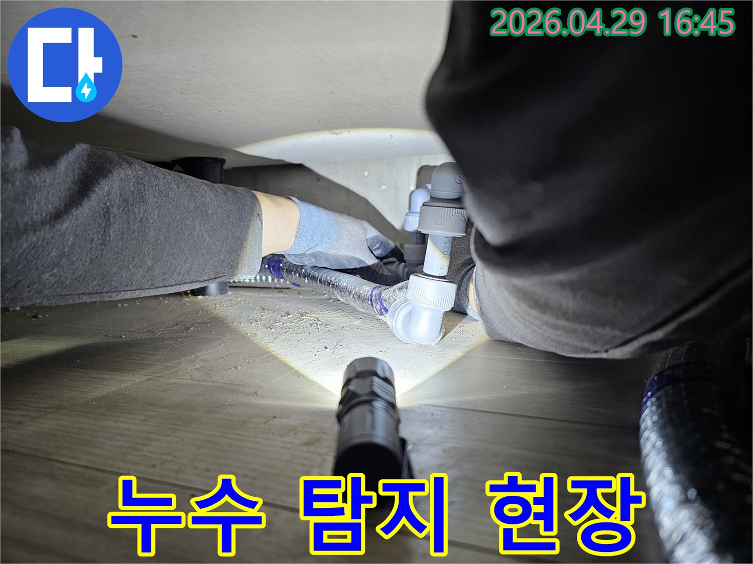 누수-탐지-전문가가-어두운-공간에서-배관-연결부를-확인하는-모습