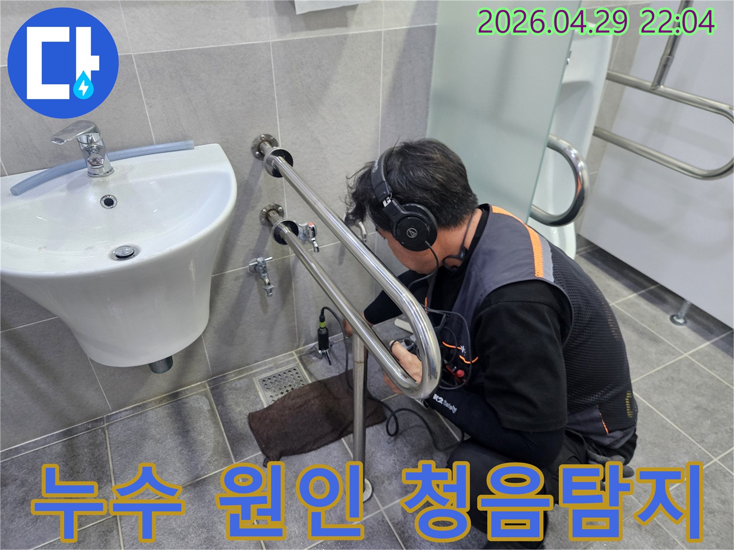 전문가가-누수탐지 장비를 이용해-화장실 배관에서 발생하는-미세한 소리를-집중적으로 듣는 모습