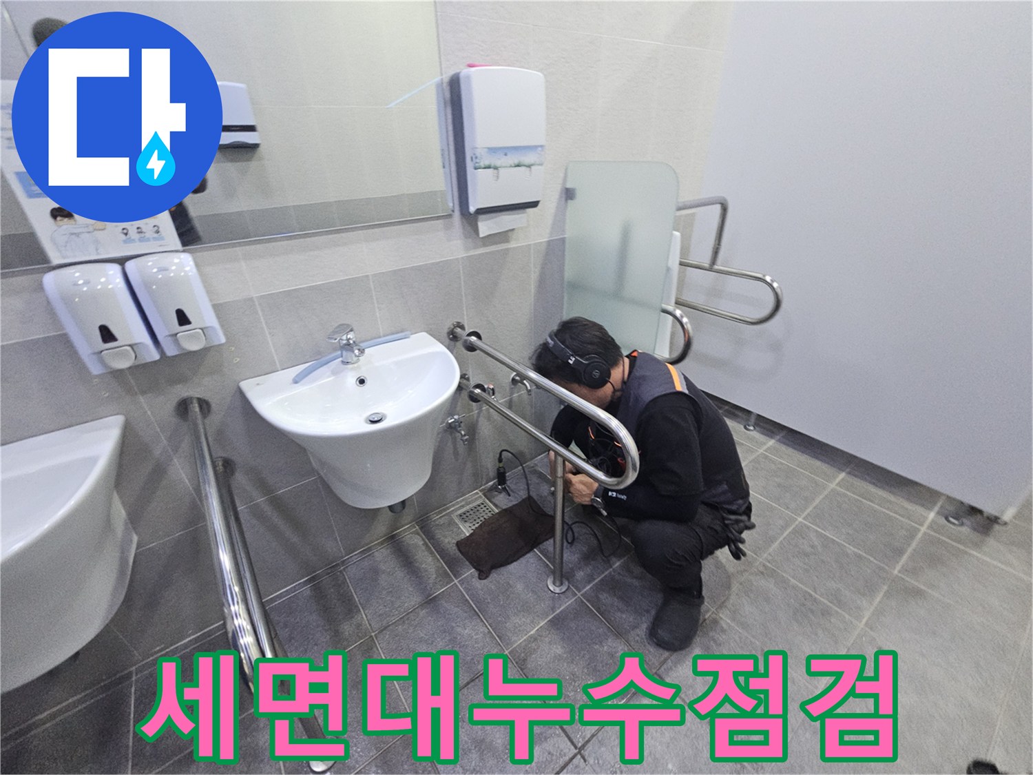 헤드폰을 착용한 기술자가-공용 화장실의 세면대 배관에서-미세한 누수 지점을 찾아내고 있습니다.