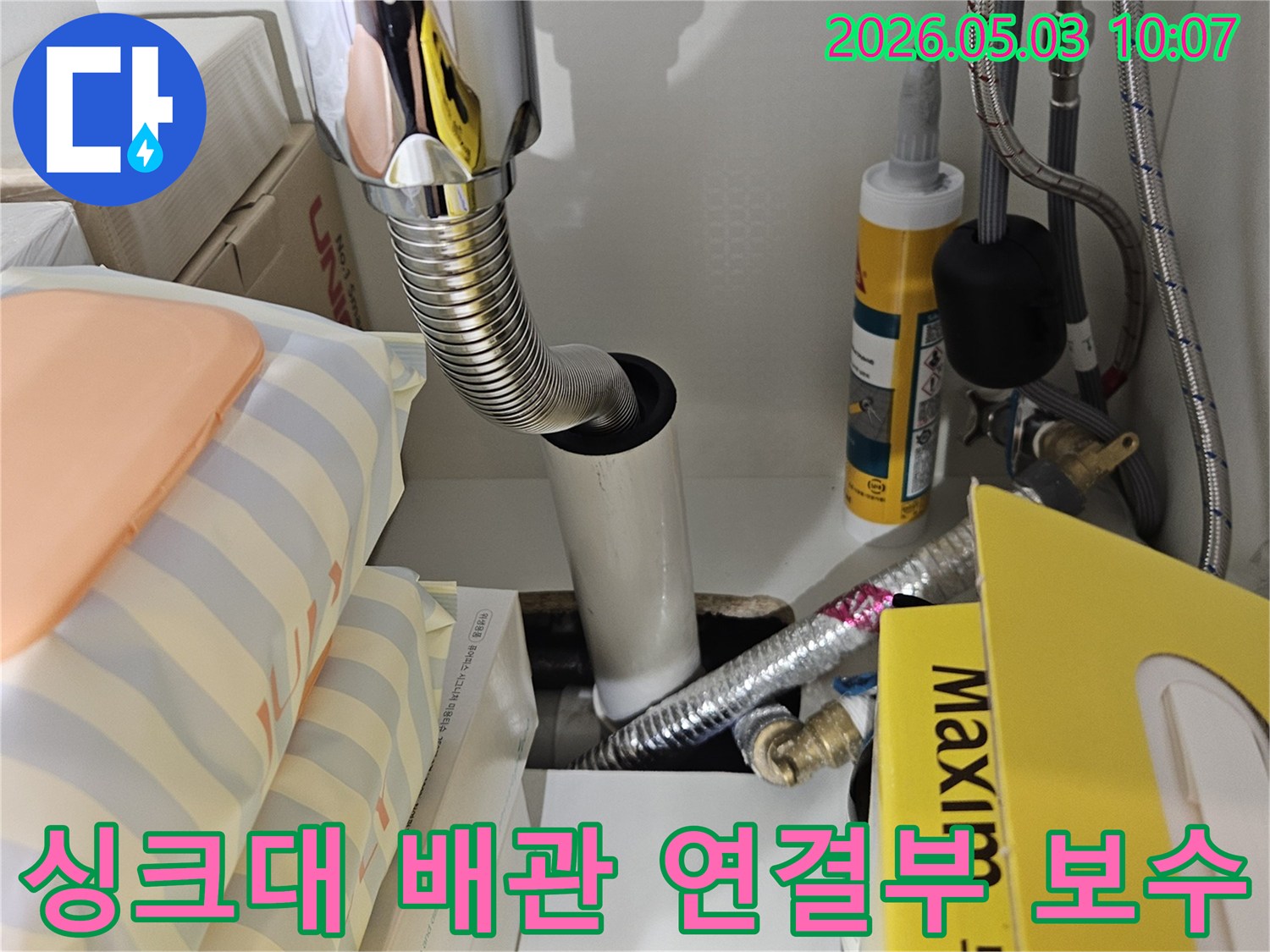 싱크대 하부의 배관 연결 부위와-유연한 호스 주변을 집중적으로 점검하여 누수 원인을 찾는 모습