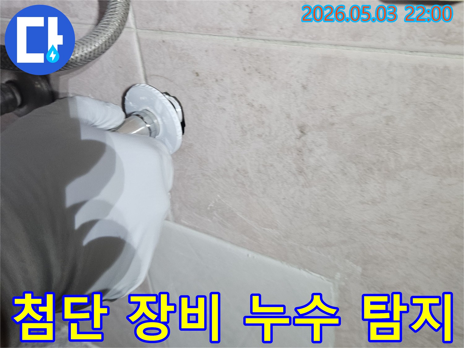 전문 엔지니어가 흰 장갑을 끼고-첨단 탐지 장비를 사용하여-벽면의 수도 배관 연결 부위를-정밀하게 검사하는 모습