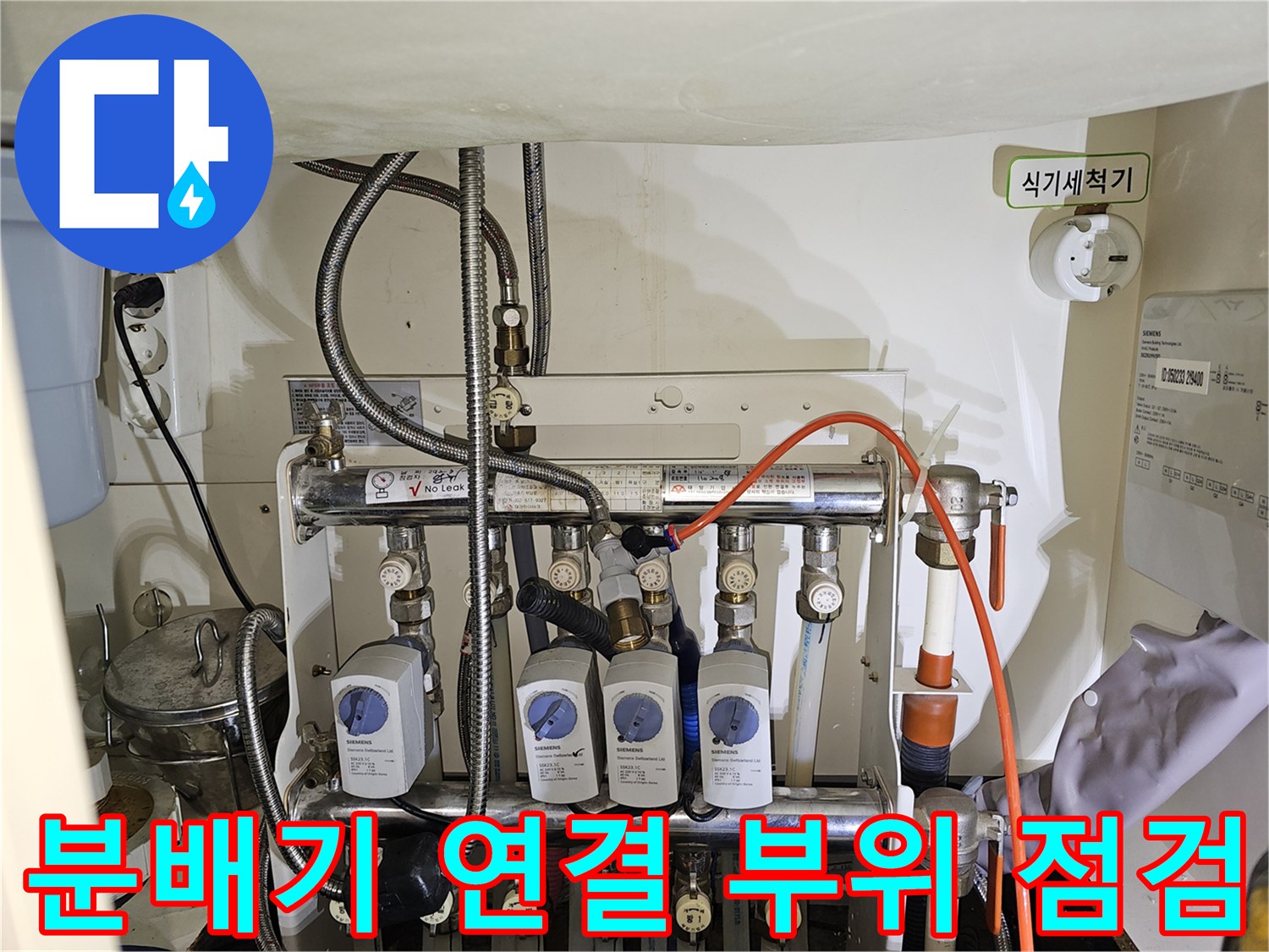 싱크대-밑-공간-내의-복잡한-난방-분배기-및-연결-호스-점검-모습