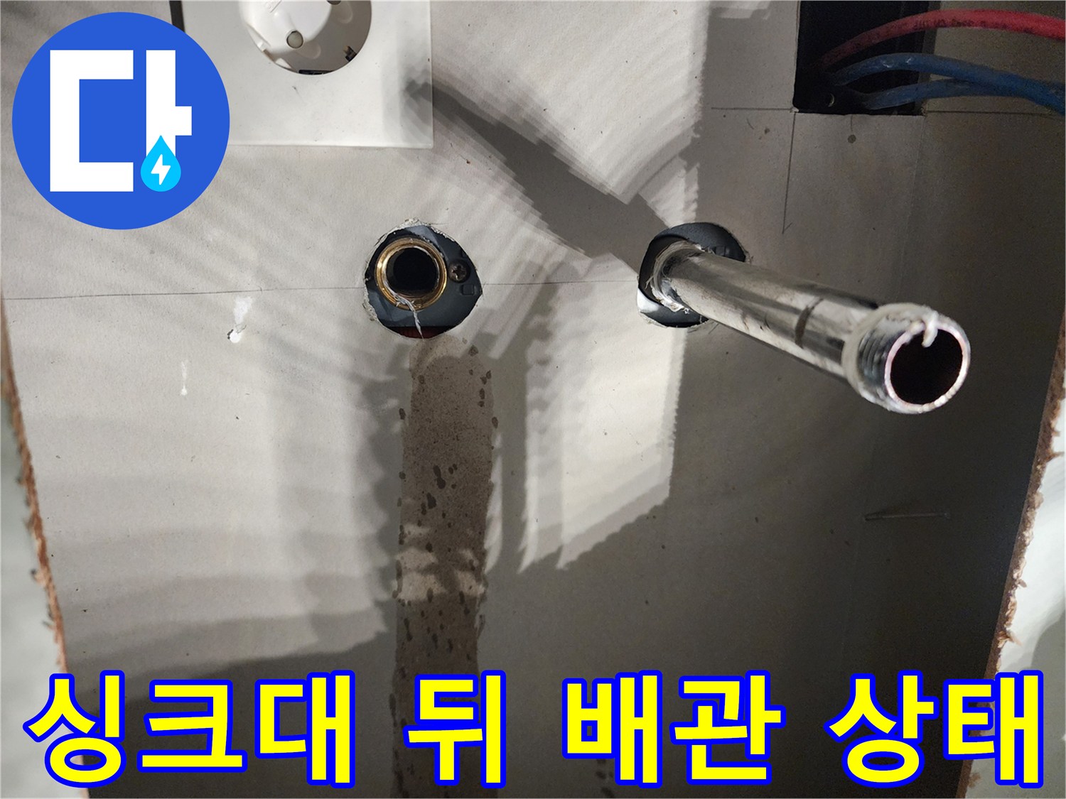 싱크대 하부장 벽면 내부의 노출된 온수 배관과 파란색 보온재 모습