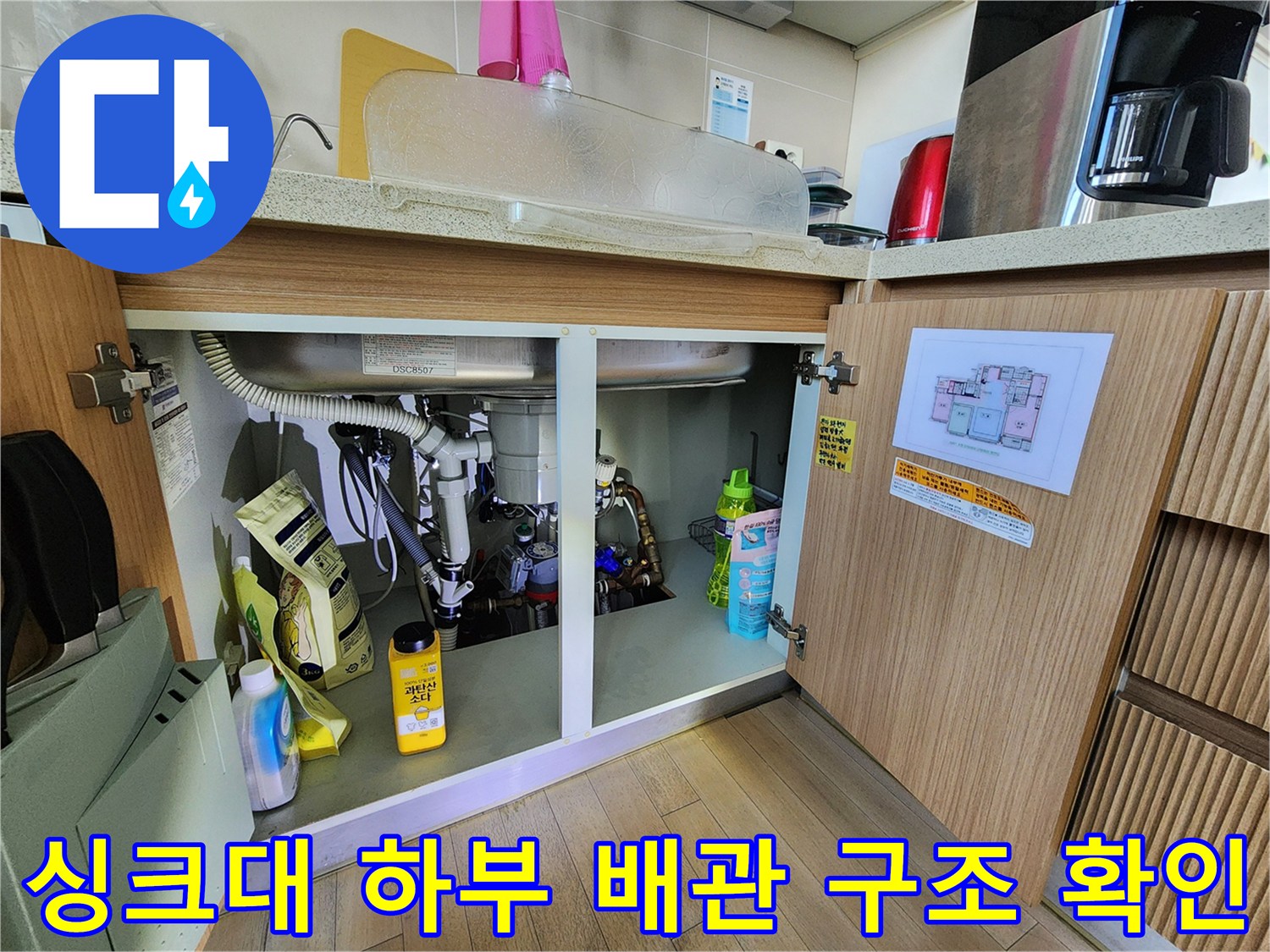 싱크대 하부장 안쪽의 복잡한 배관 연결 및 점검 모습