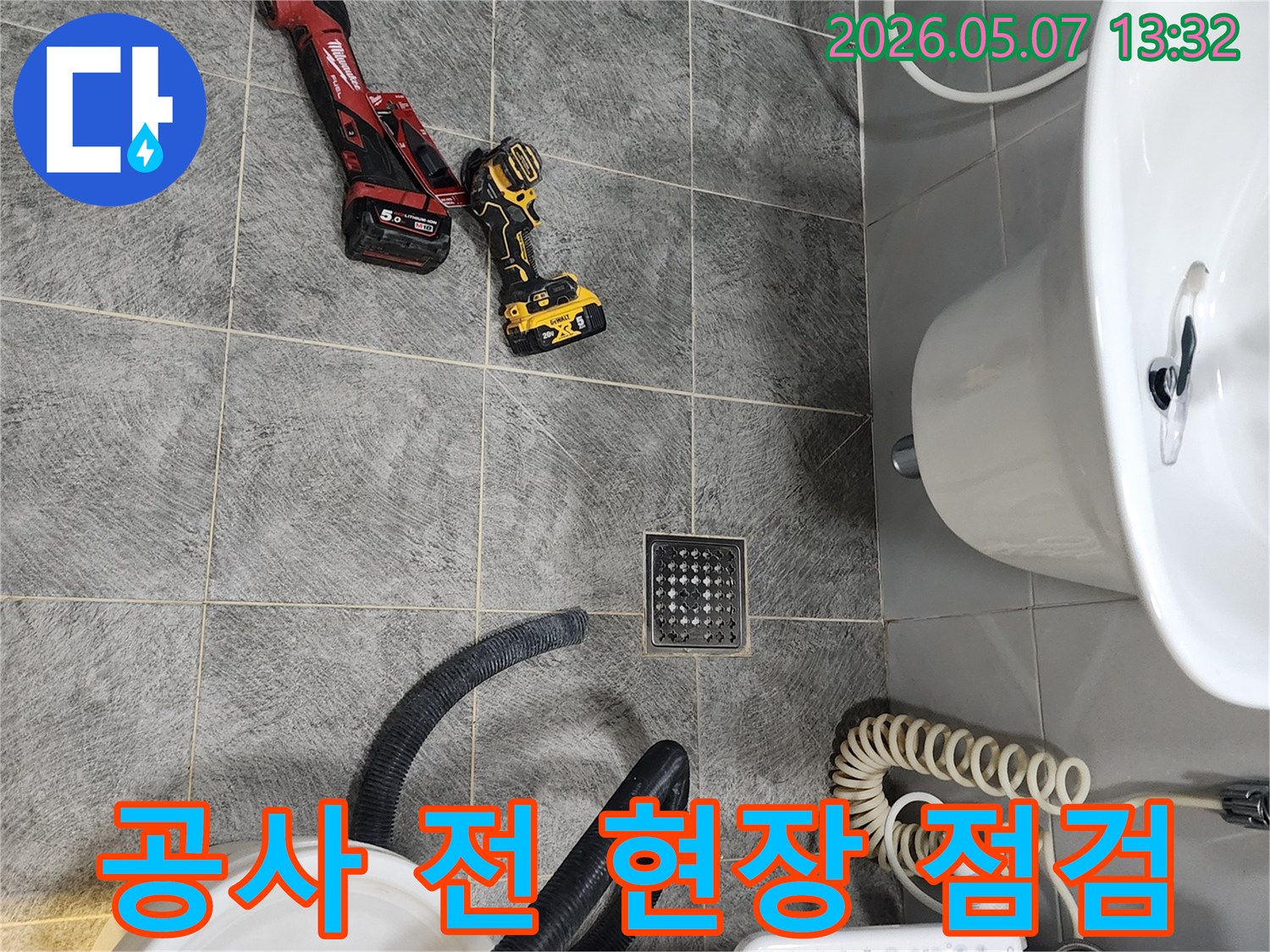 욕실 바닥에 놓인 누수-탐지 공구들과 세면대-변기가 보이는 공사-시작 전 현장 사진입니다.