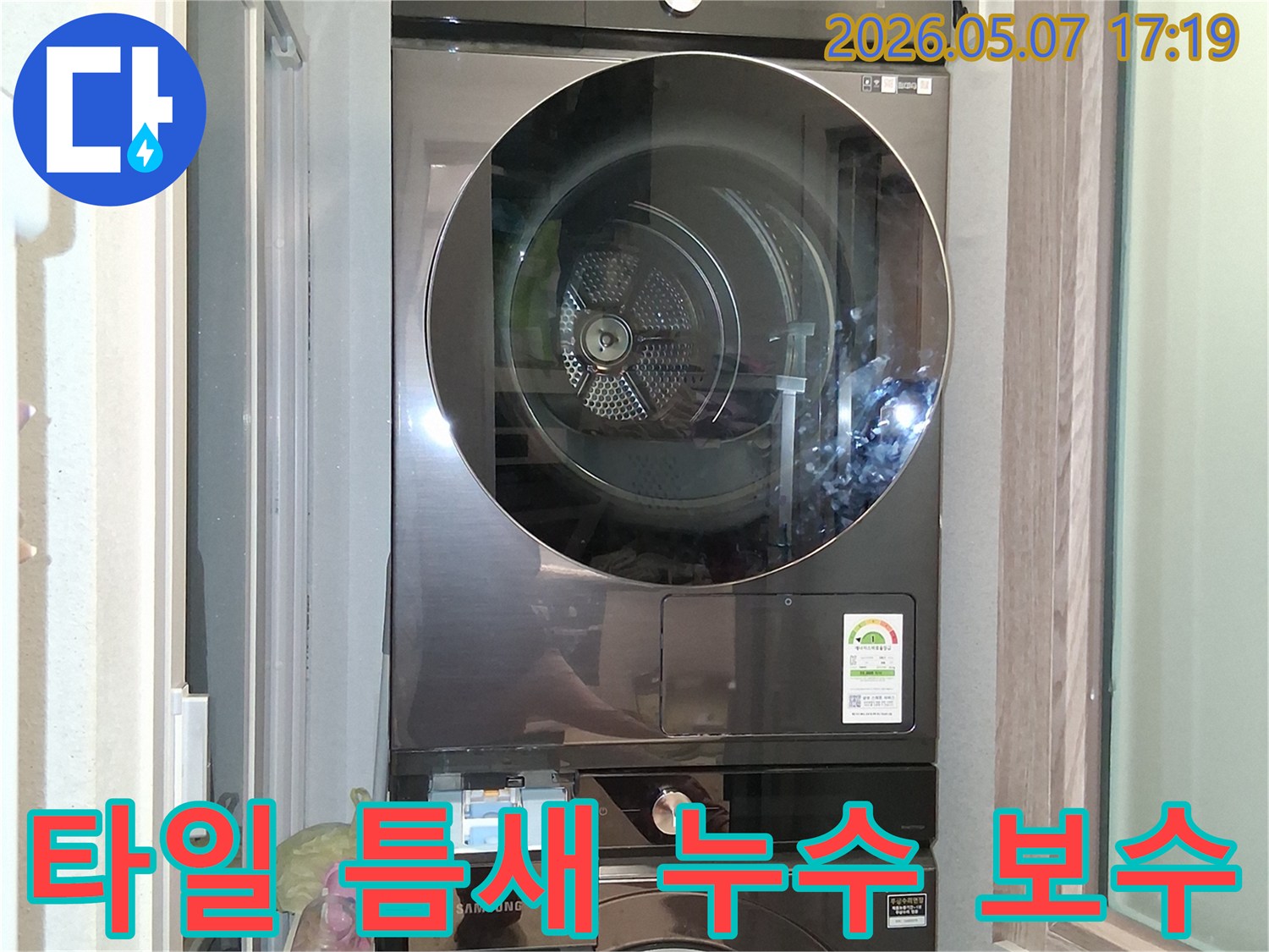 세탁실의-삼성 세탁기와 건조기-주변 바닥 타일-틈새에서-누수 흔적을-확인하고-보수 작업을-준비하는-모습입니다