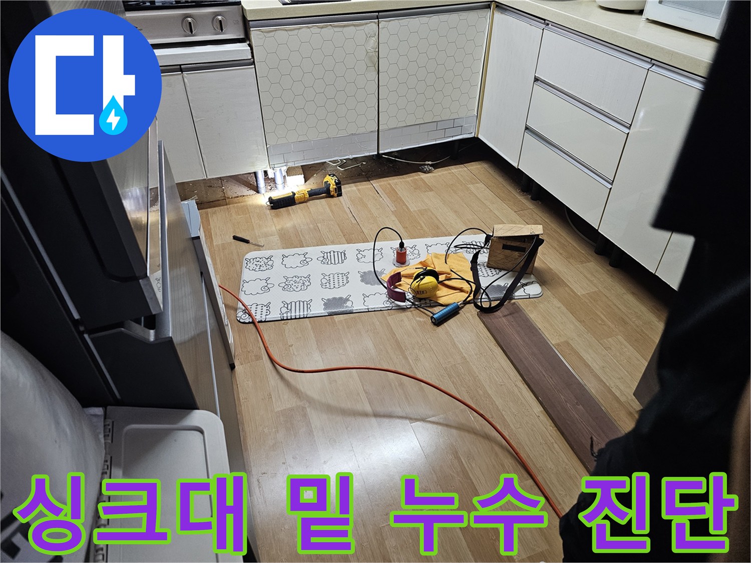 누수 탐지를 위해 싱크대 아래 공간에 배치된 가스 탐지기와 공구