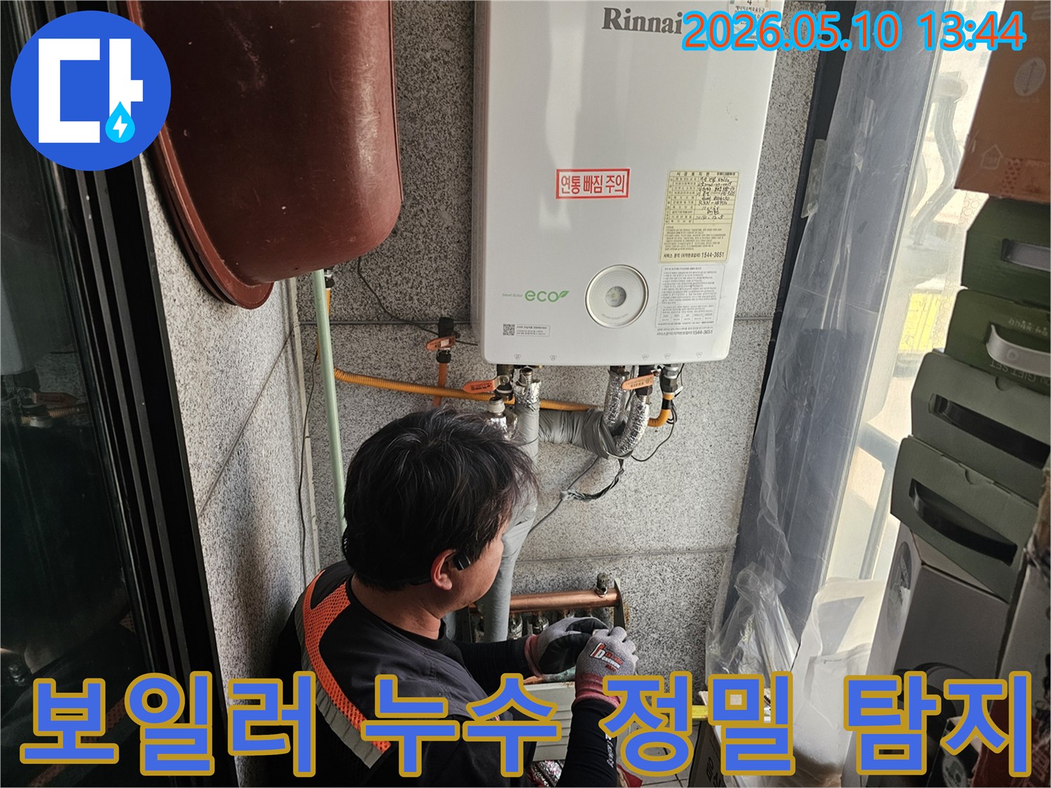 전문가가-고객 댁 보일러 하부-배관 연결 부위의-누수를 면밀히 살피는 모습
